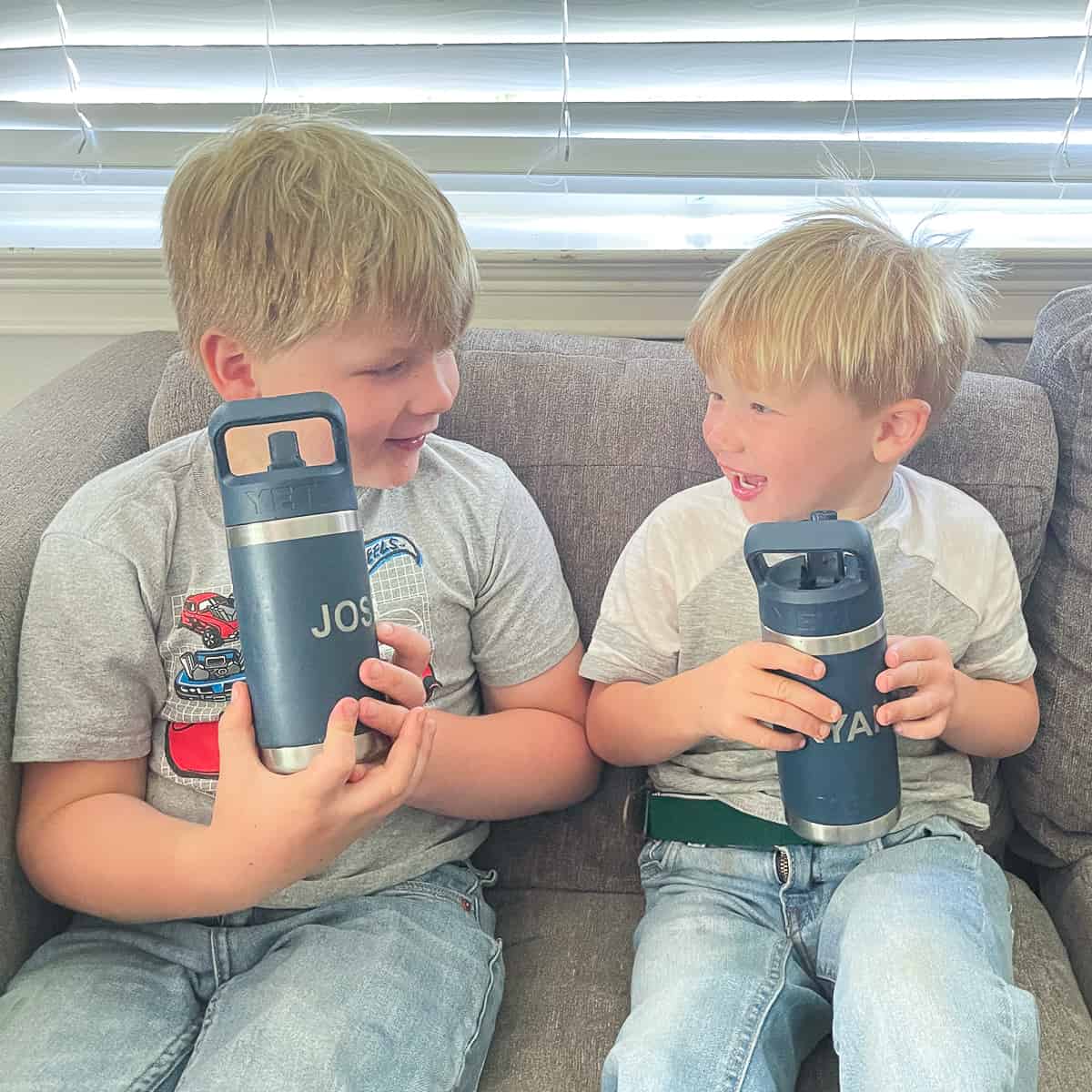 2 little boys drinking from reusable water bottles