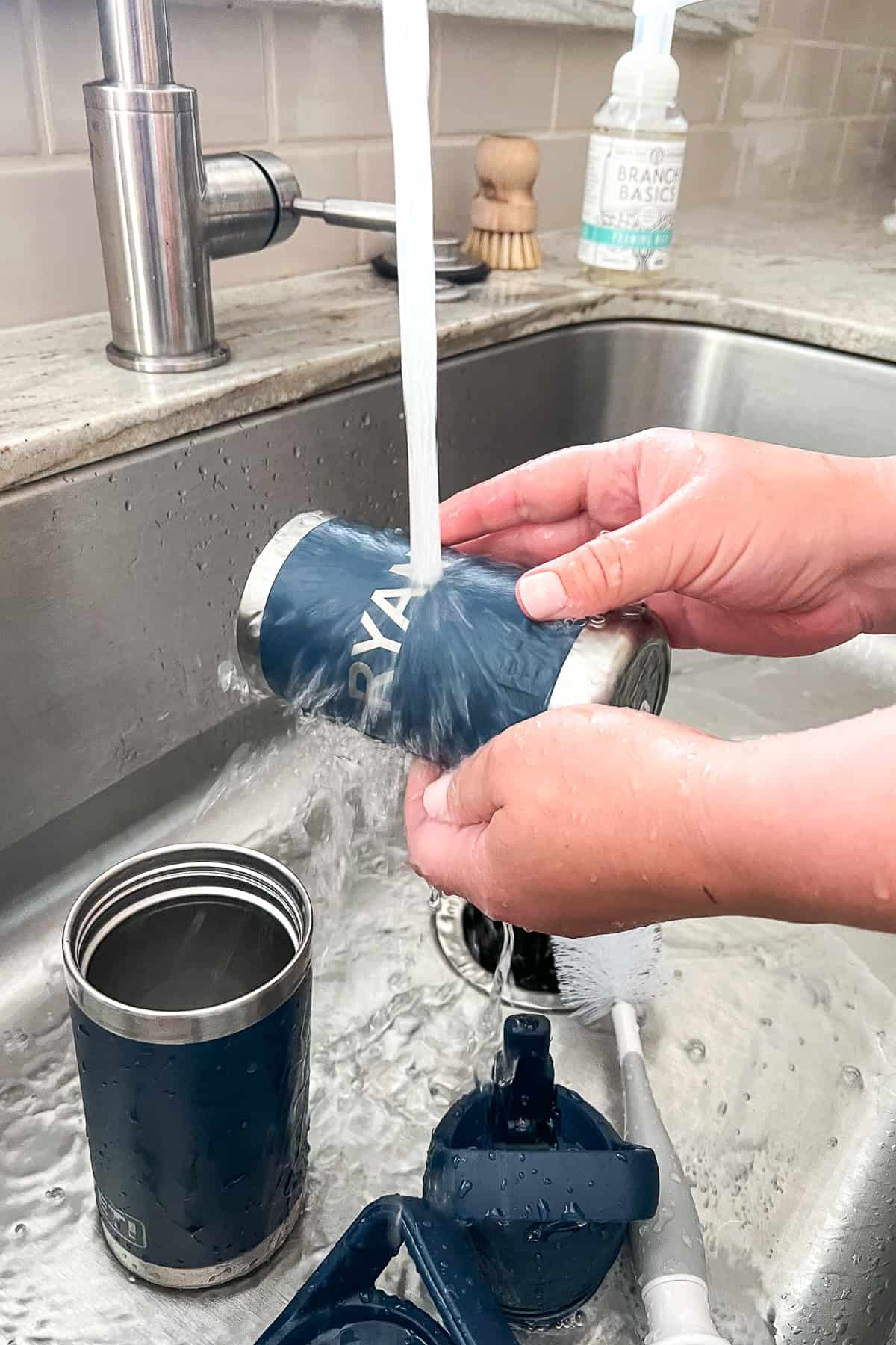 rinsing cleaned stainless steel water bottles in water in the sink