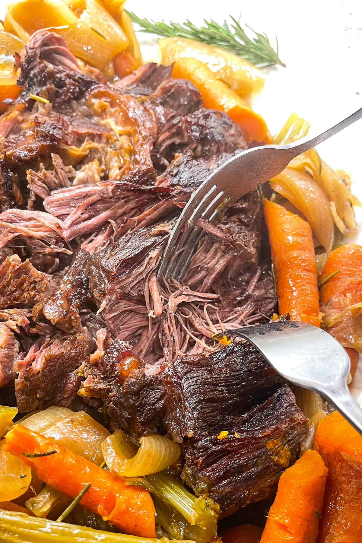 a closeup photo of a fork slicing a piece of beef from the dutch oven pot roast recipe