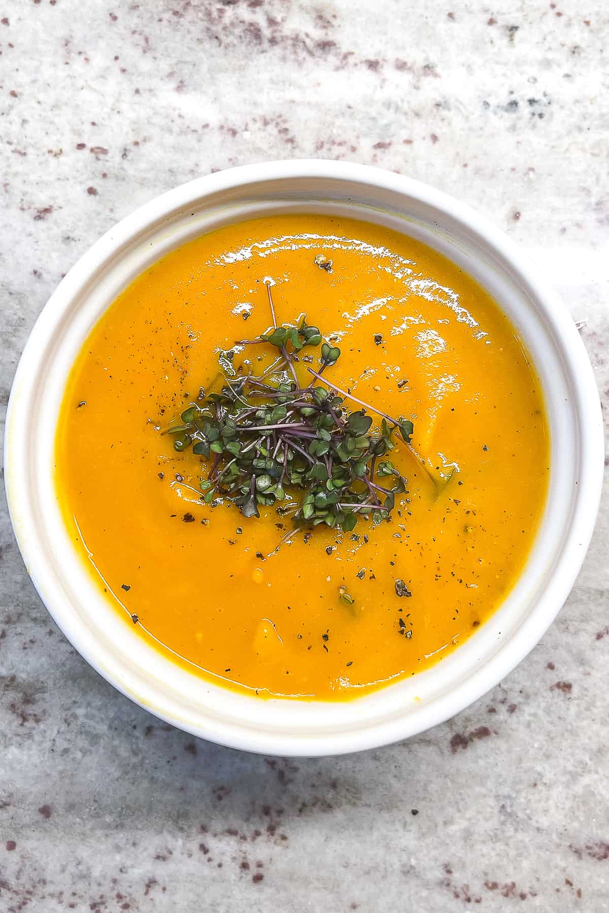 and overhead shot of a white bowl filled with butternut squash soup 