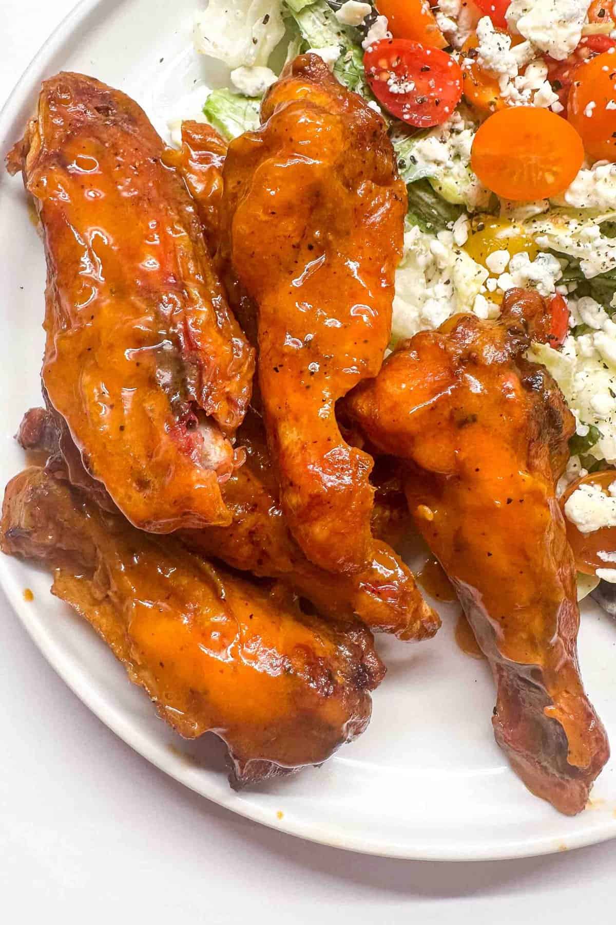 a close up of smoked buffalo wings on a white plate