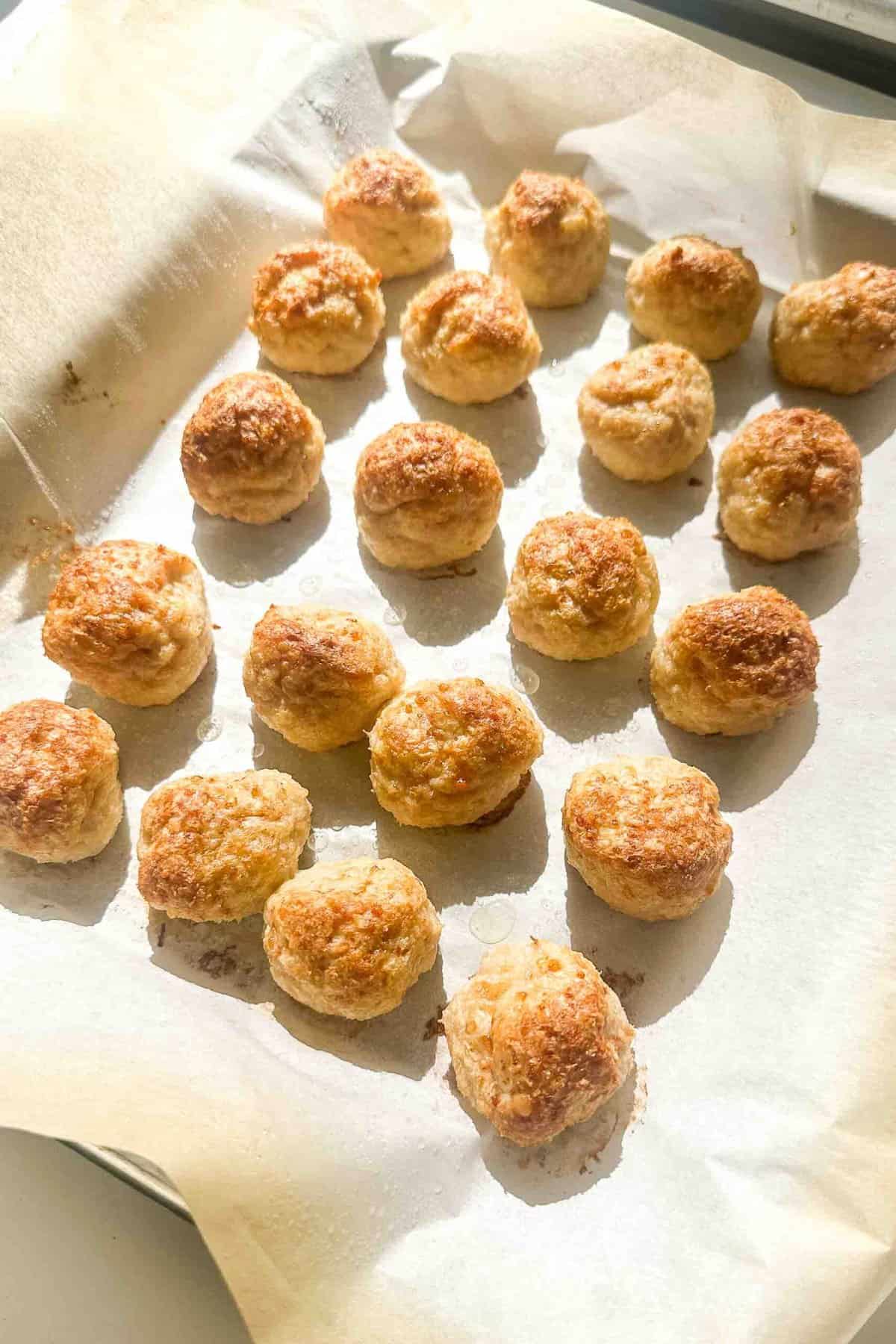 a photo of chicken meatballs on a lined baking sheet