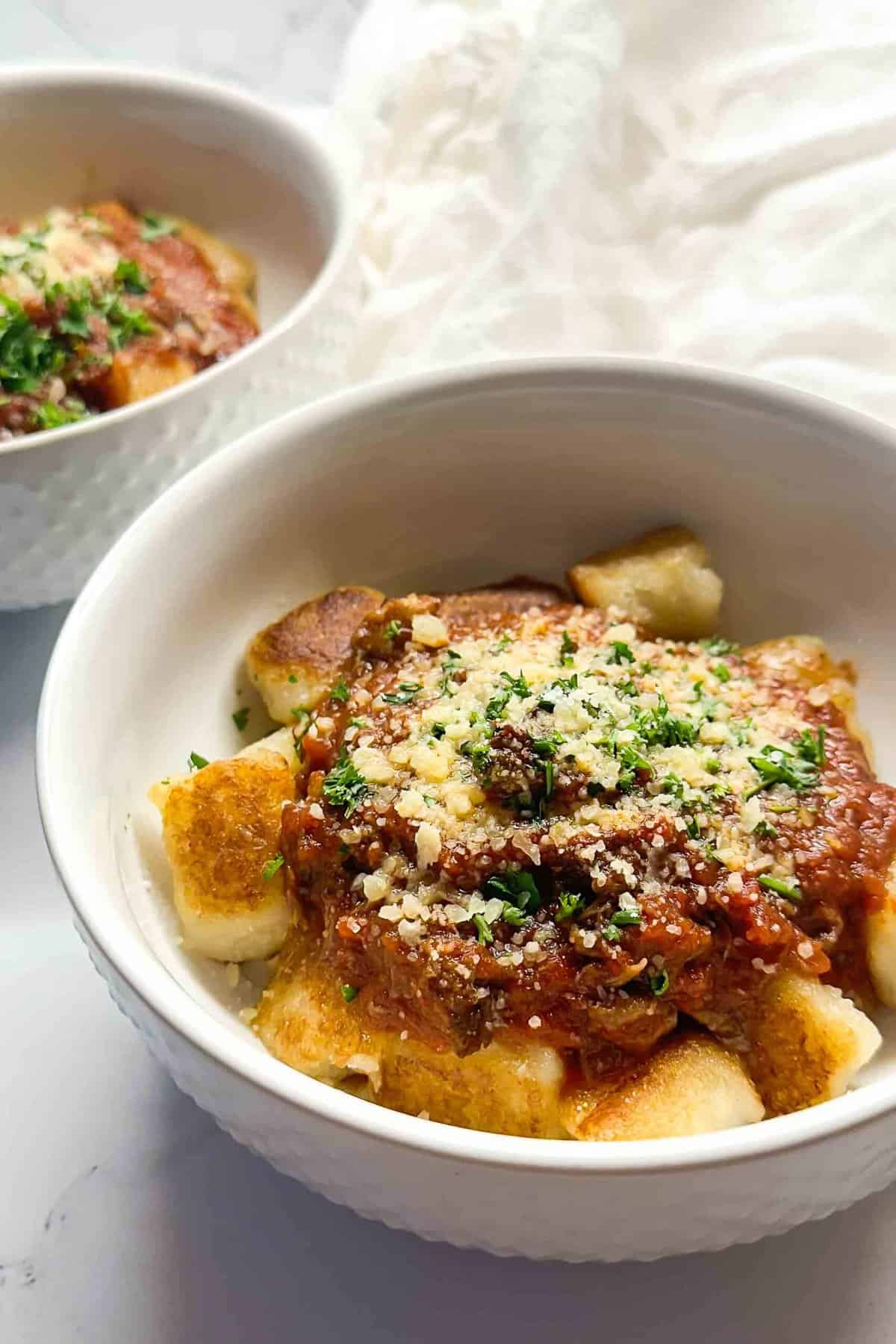 a bowl of instant pot beef ragu topped with parsley and parmesan cheese