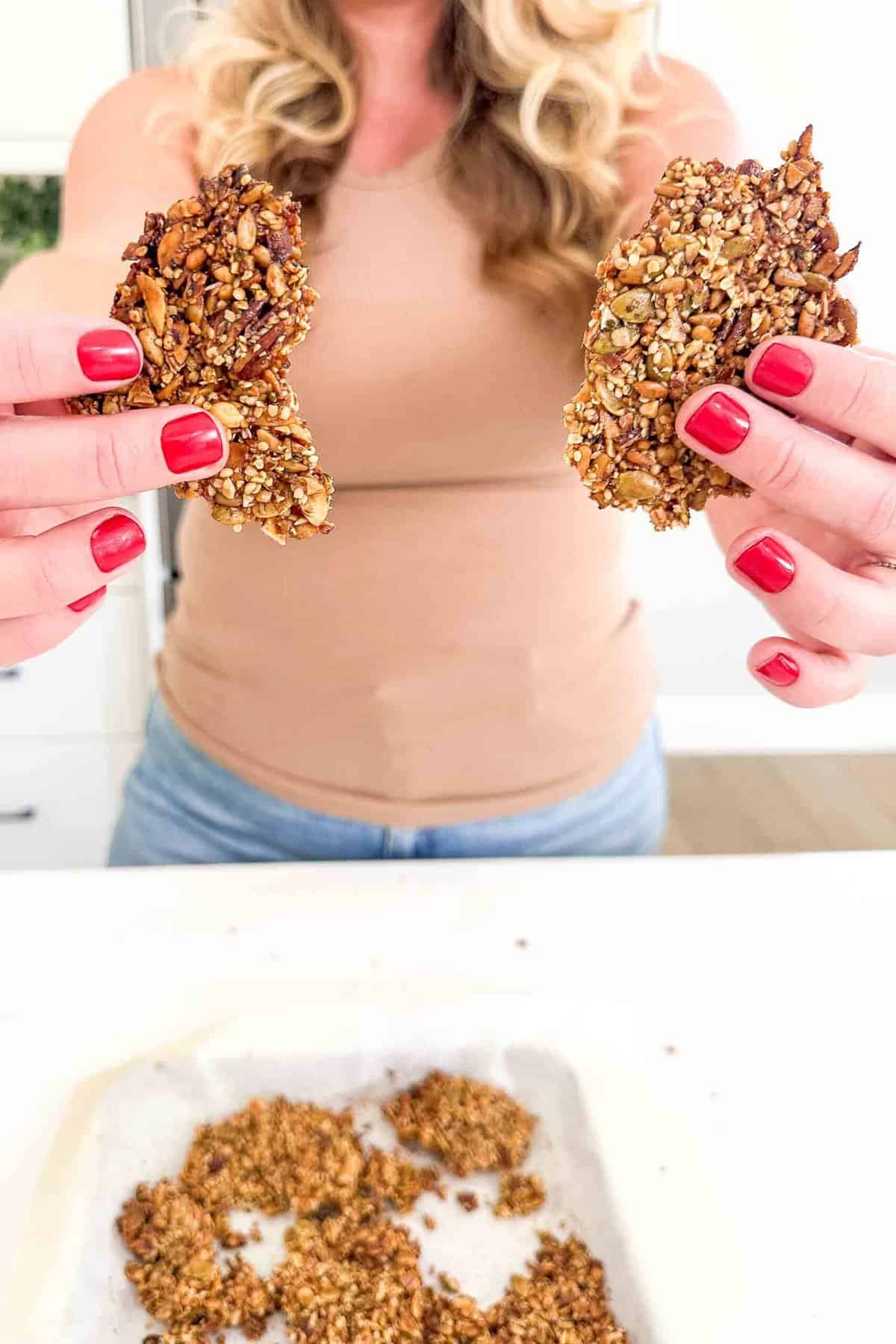 hands holding two pieces of grain free granola 