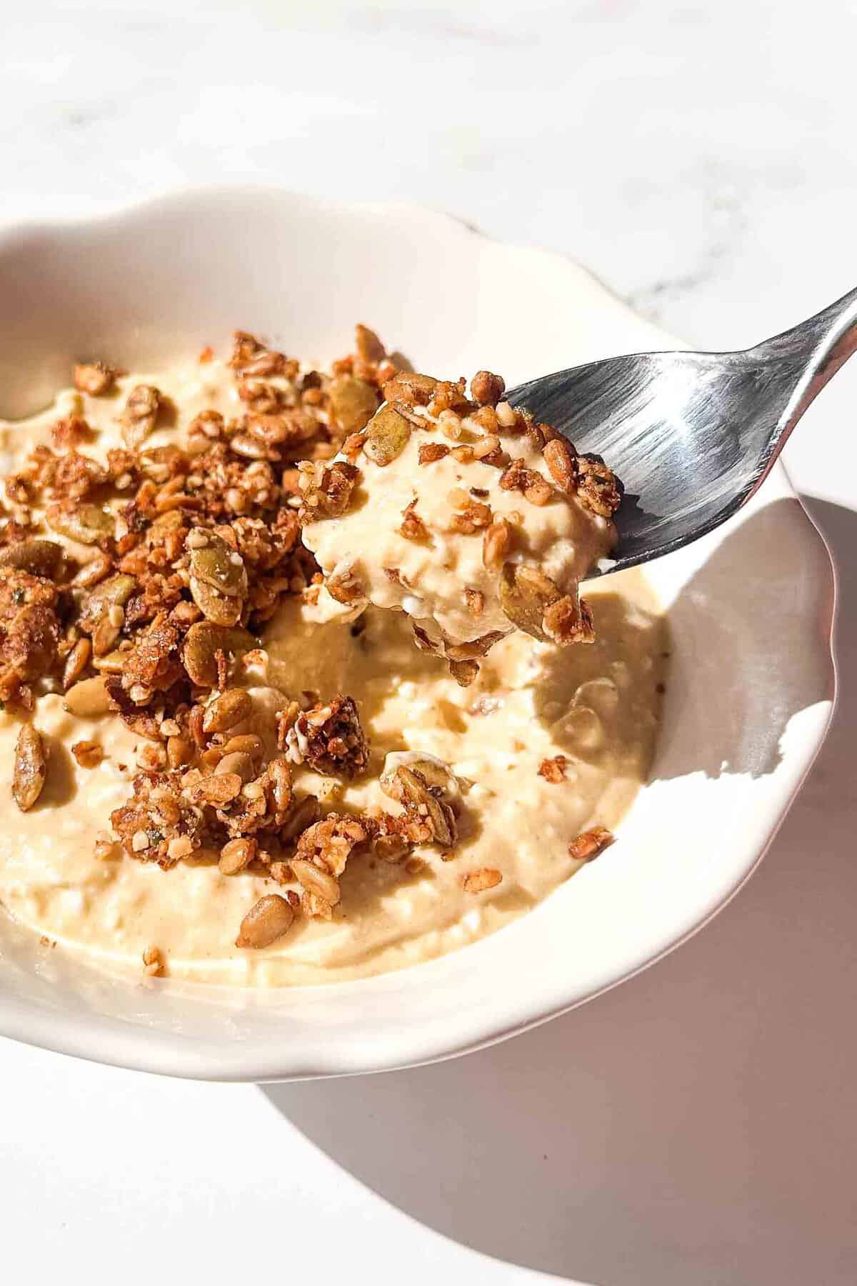 a spoon lifting a bite of cheesecake out of the bowl 