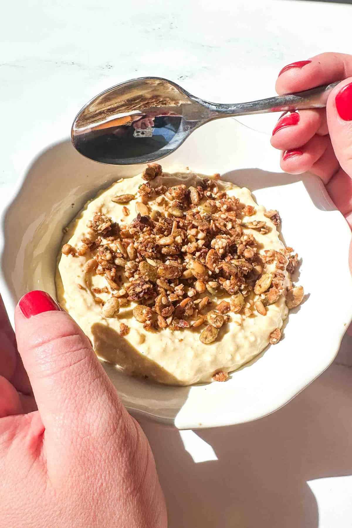 a hand holding a protein cheesecake bowl with a spoon 