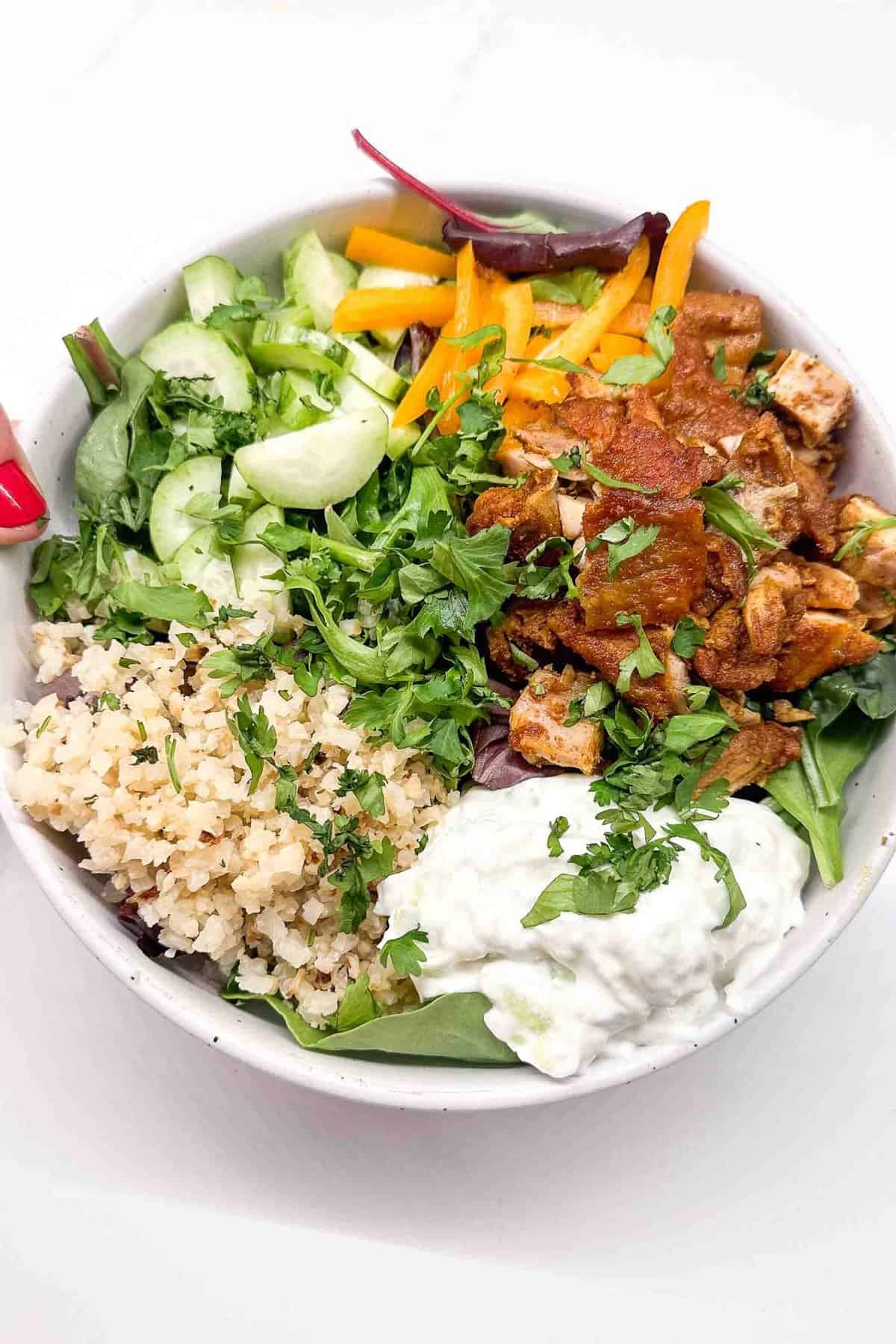 chicken shawarma bowls filled with rice, tzatziki, greens, and fresh veggies
