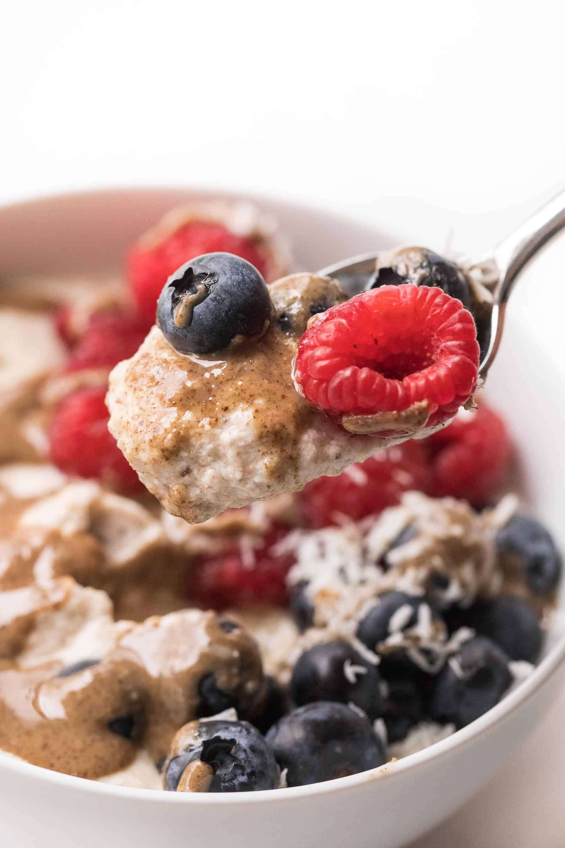 a spoon of breakfast porridge with berries and nut butter
