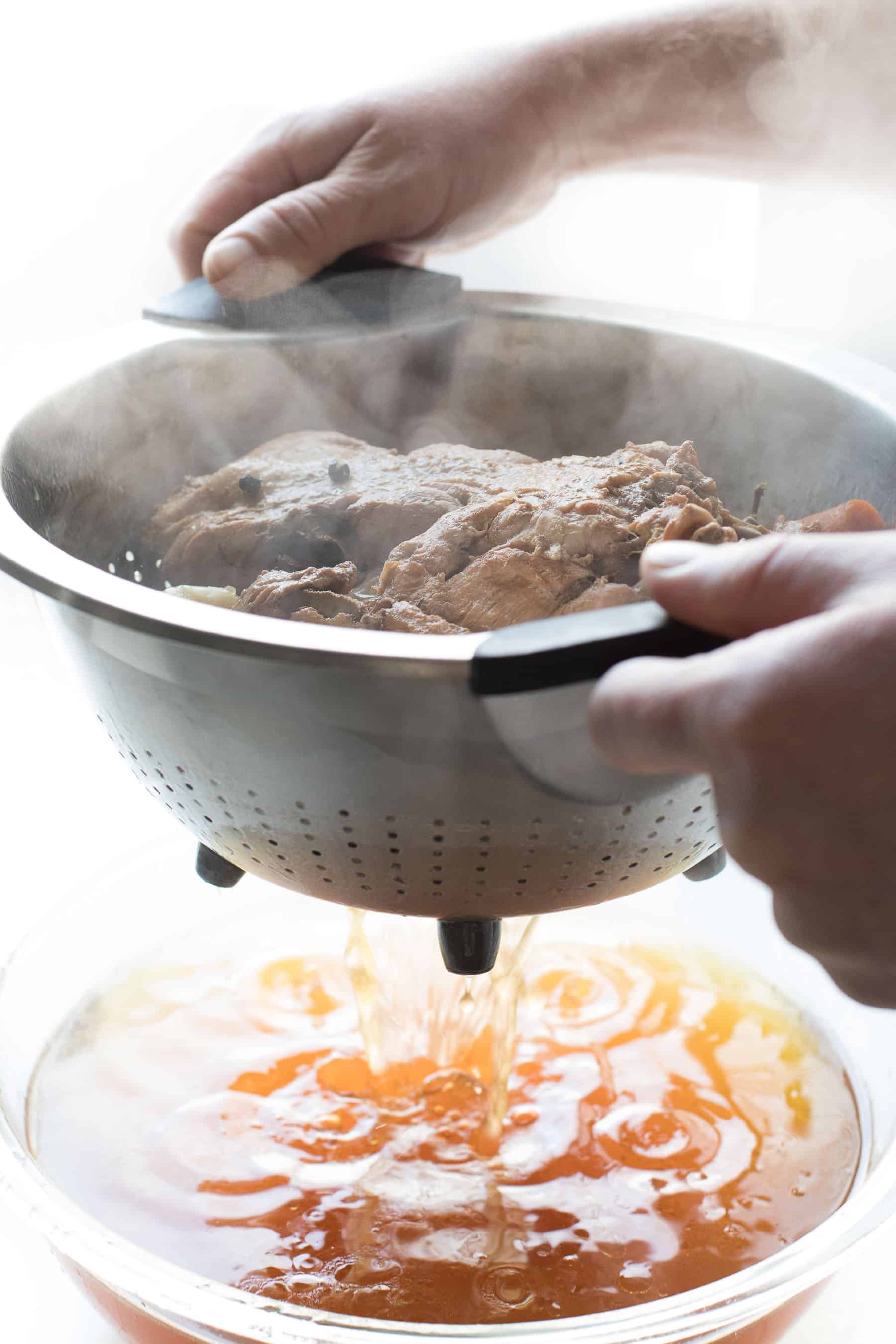 straining bone broth through a collander