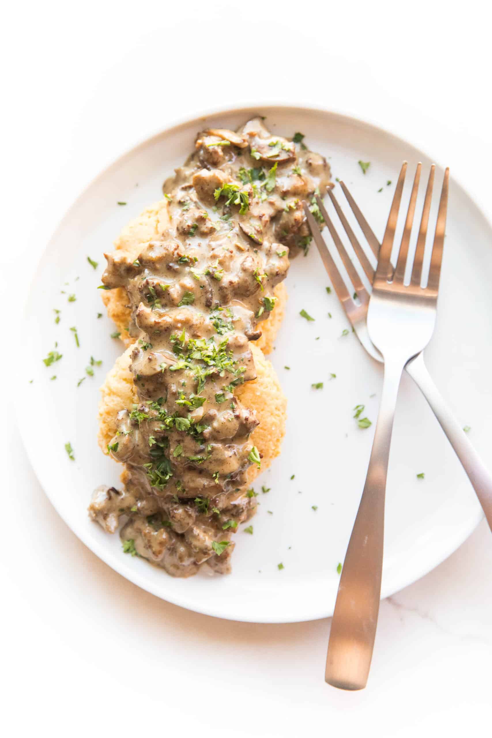 KETO BISCUITS AND GRAVY ON A WHITE PLATE