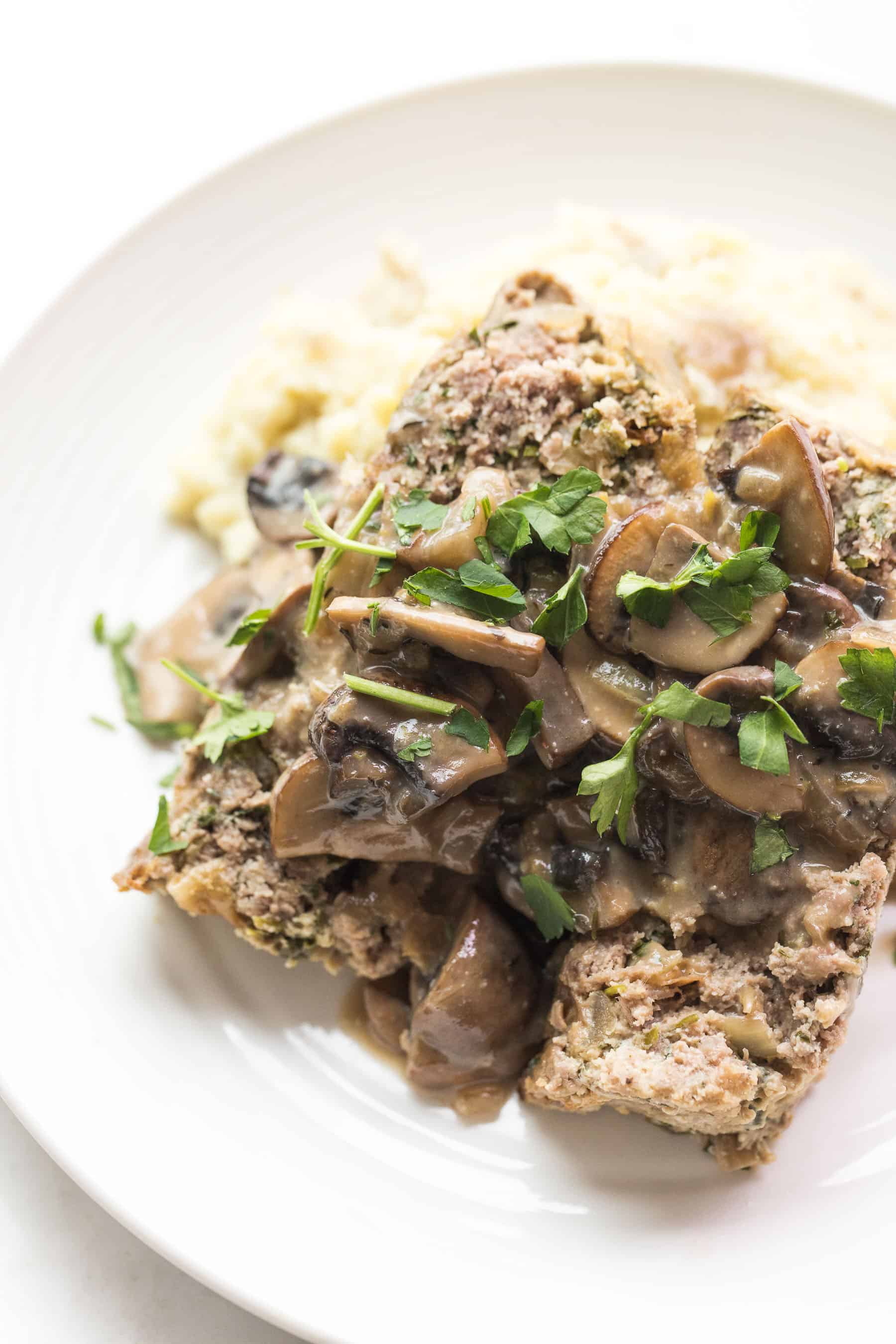 White plate with meatloaf and mushroom gravy over mashed potatoes