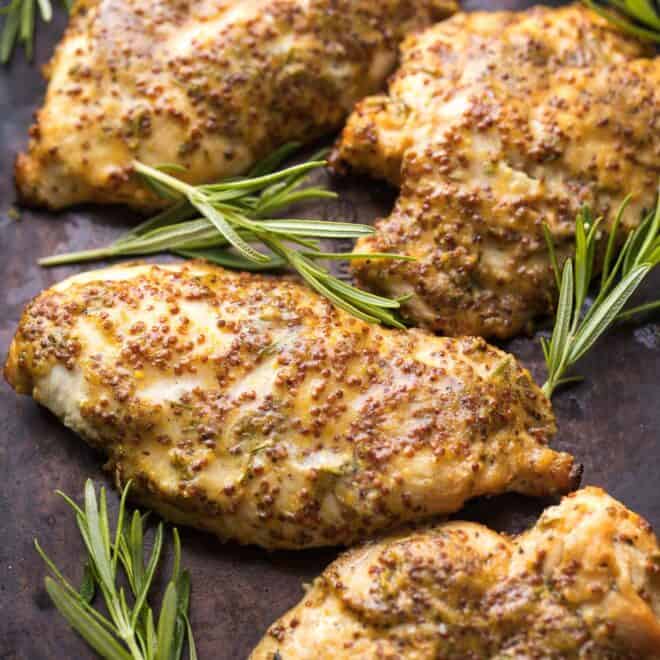 baked chicken breasts resting next to sprigs of rosemary