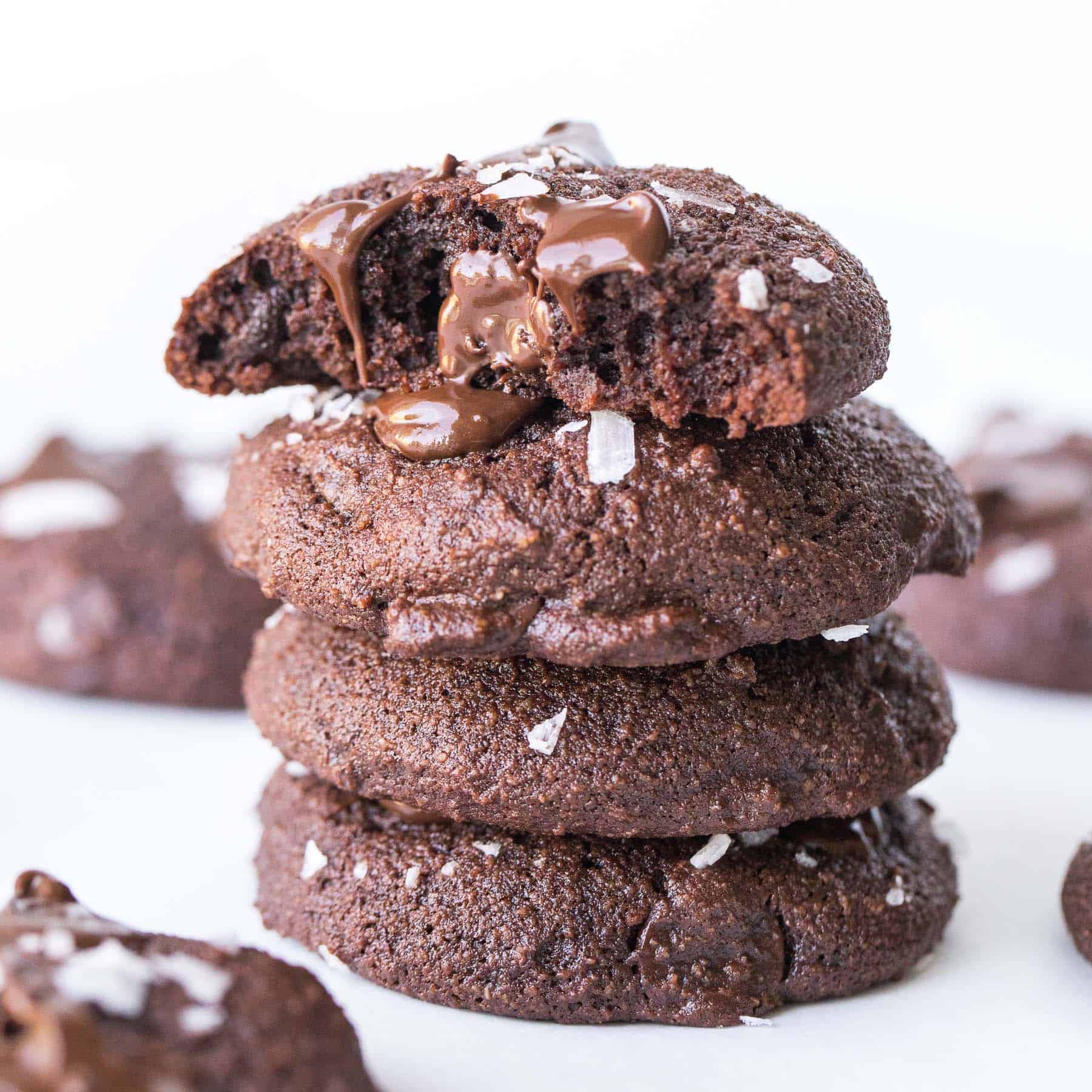 a stack of four chocolate cookies with a bite taken out of the top cookie