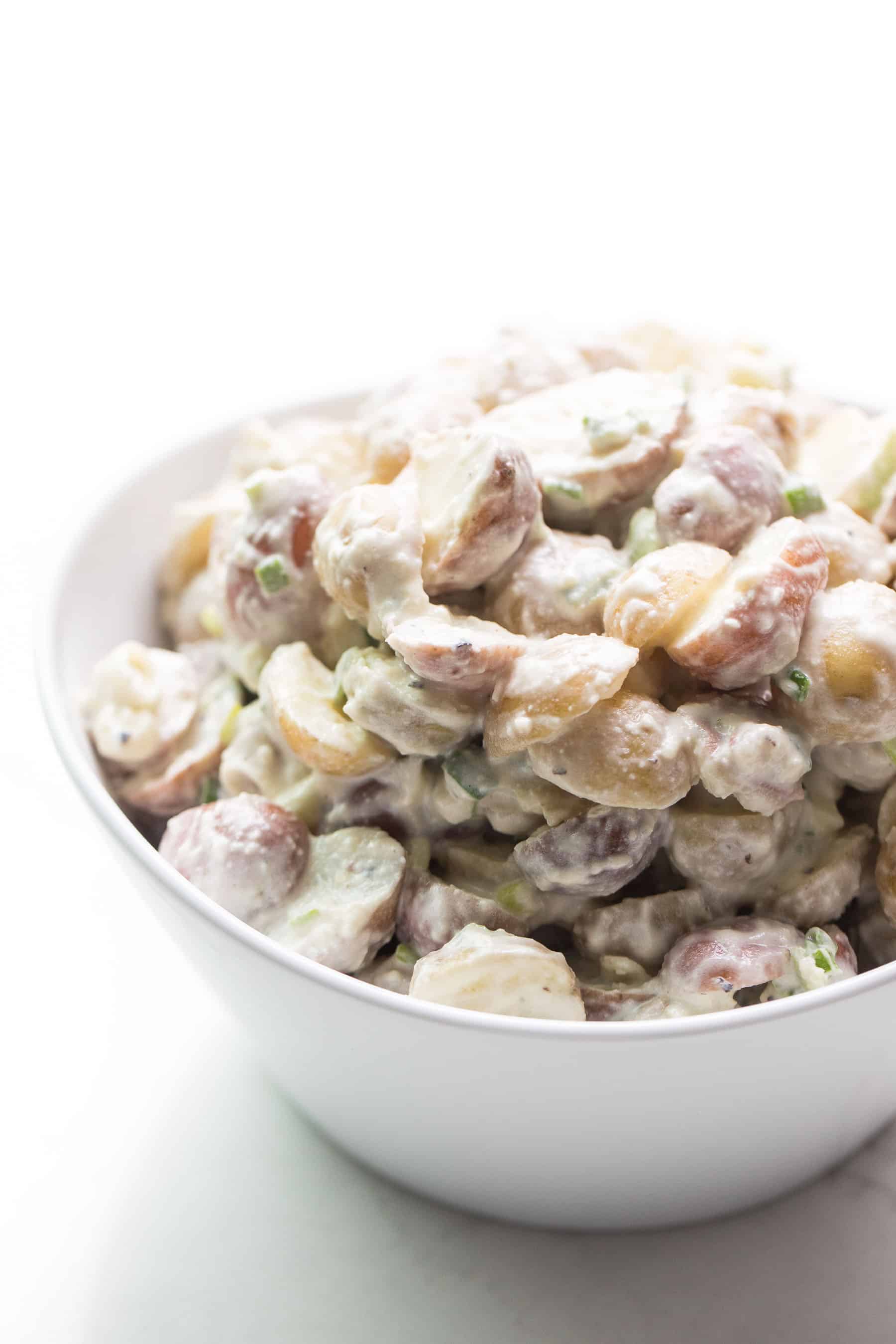 Potato salad in a white bowl on white background