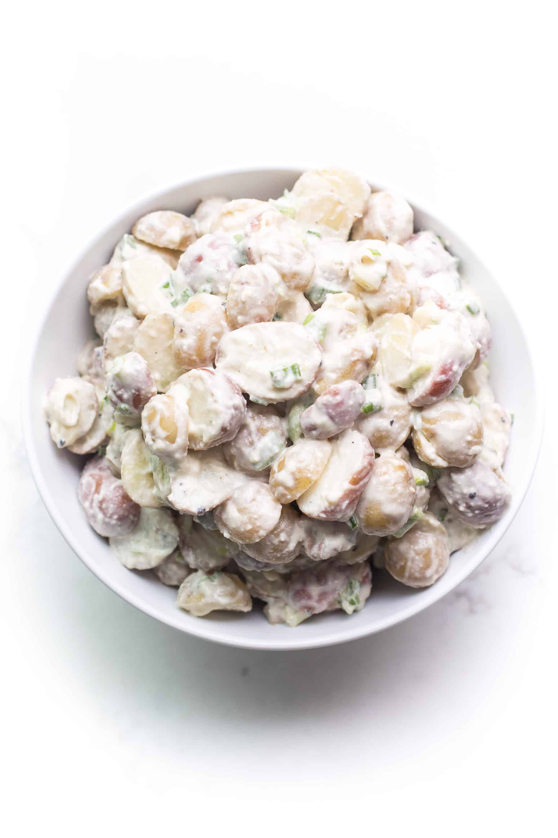 potato salad in a white bowl on a white background