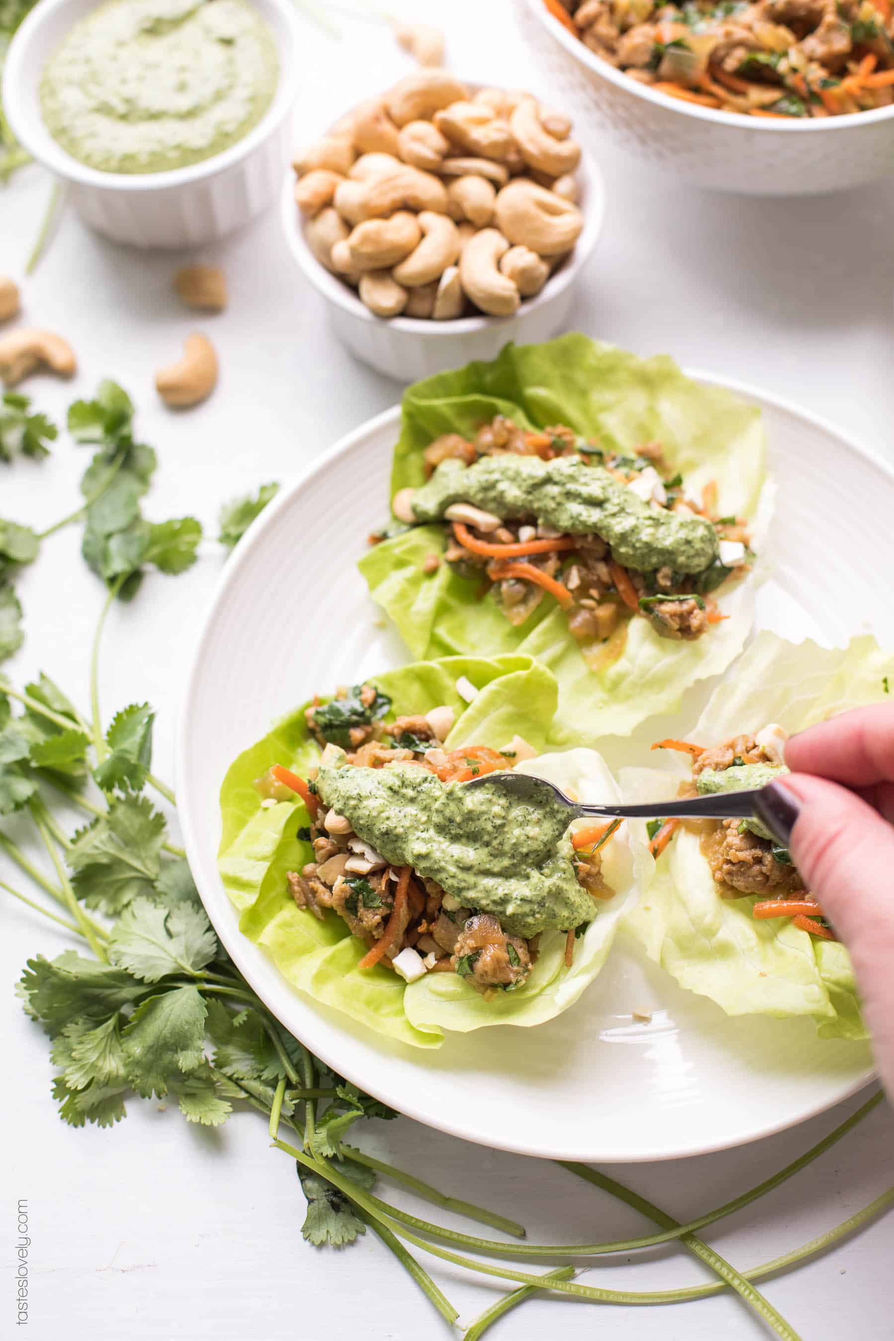 Paleo + Whole30 Thai Chicken Lettuce Wraps - a quick and healthy dinner recipe with ground chicken, sauteed onions, a thai sauce, cilantro and shredded carrots. Topped with a bright and fresh herby green dressing and cashews. #paleo #whole30 #glutenfree #grainfree #dairyfree #sugarfree #keto #cleaneating #realfood