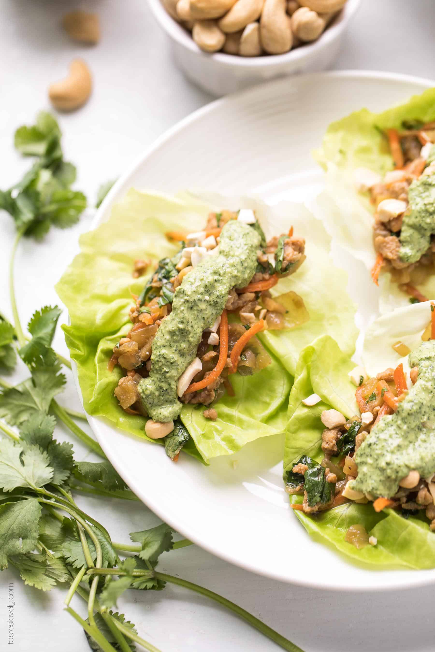 Paleo + Whole30 Thai Chicken Lettuce Wraps - a quick and healthy dinner recipe with ground chicken, sauteed onions, a thai sauce, cilantro and shredded carrots. Topped with a bright and fresh herby green dressing and cashews. #paleo #whole30 #glutenfree #grainfree #dairyfree #sugarfree #keto #cleaneating #realfood