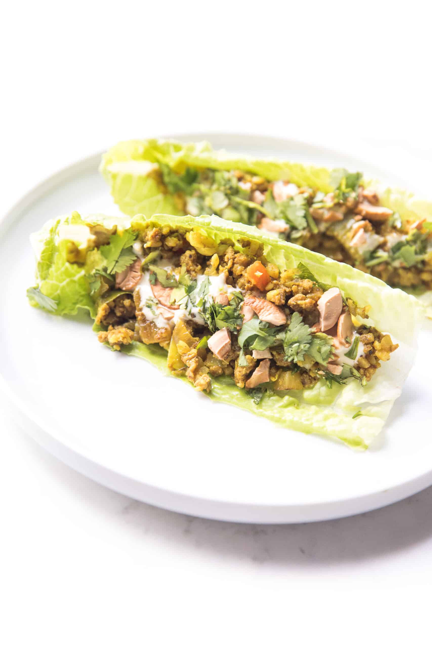 Curry lettuce wraps with cashews and cilantro on a white plate