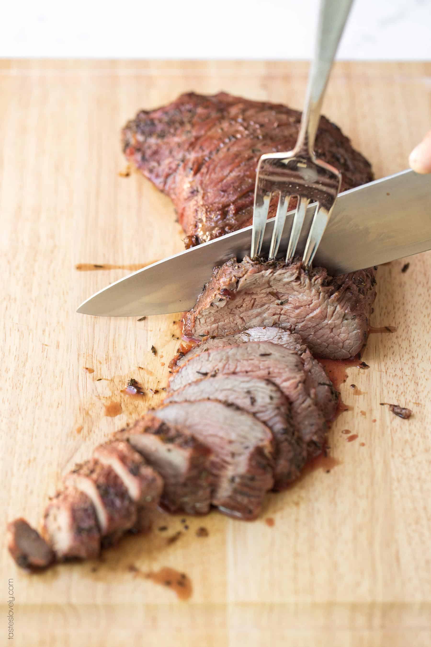 a knife slicing tri tip into thin slices