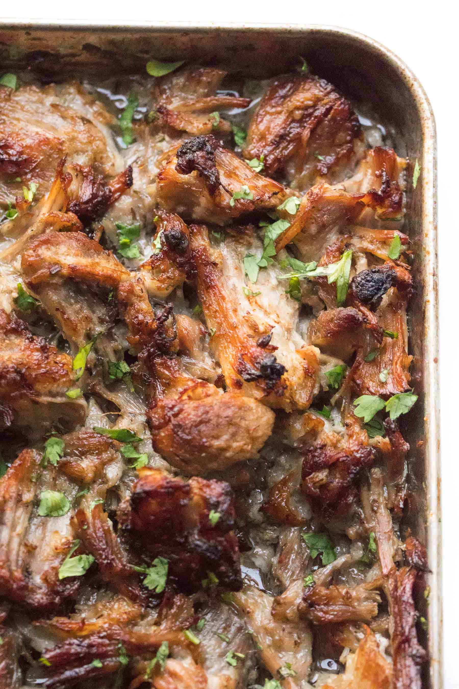 Crispy intant pot carnitas on a sheet pan sprinkled with cilantro