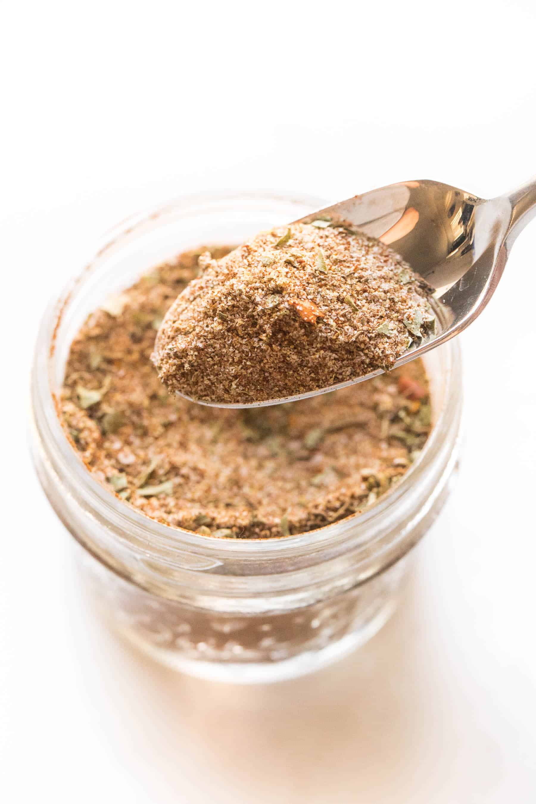 spoon holding jamaican jerk seasoning on a white background