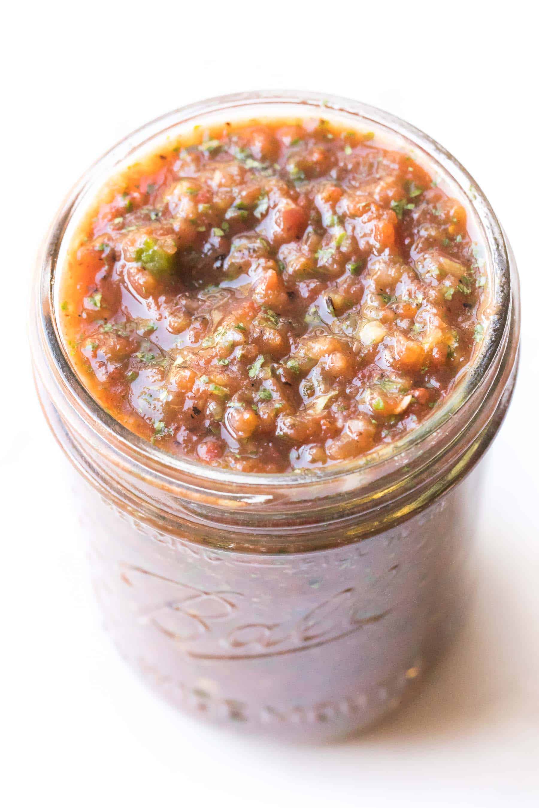 homemade red salsa in a mason jar on a white background