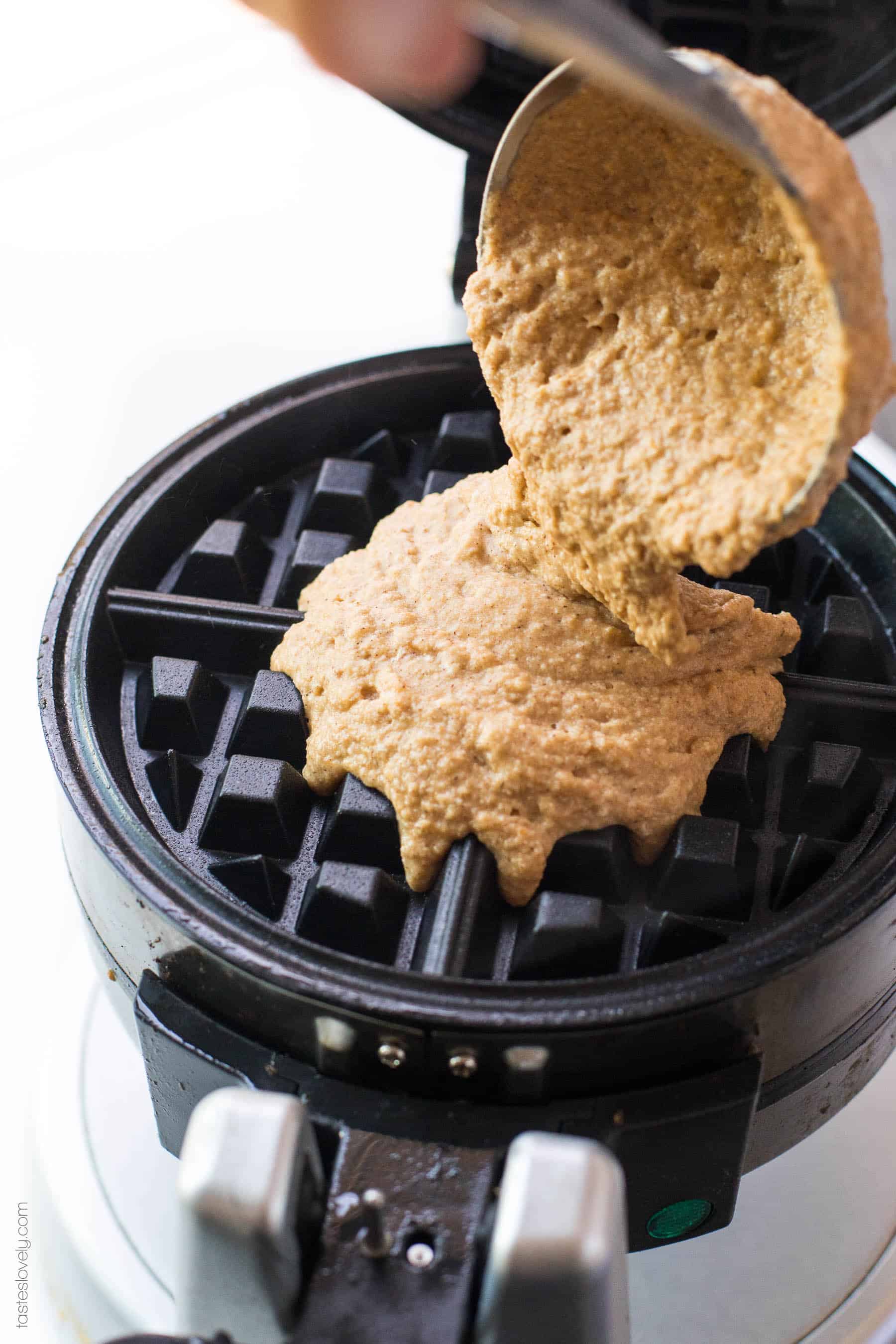 pumpkin waffle batter being poured into a waffle iron