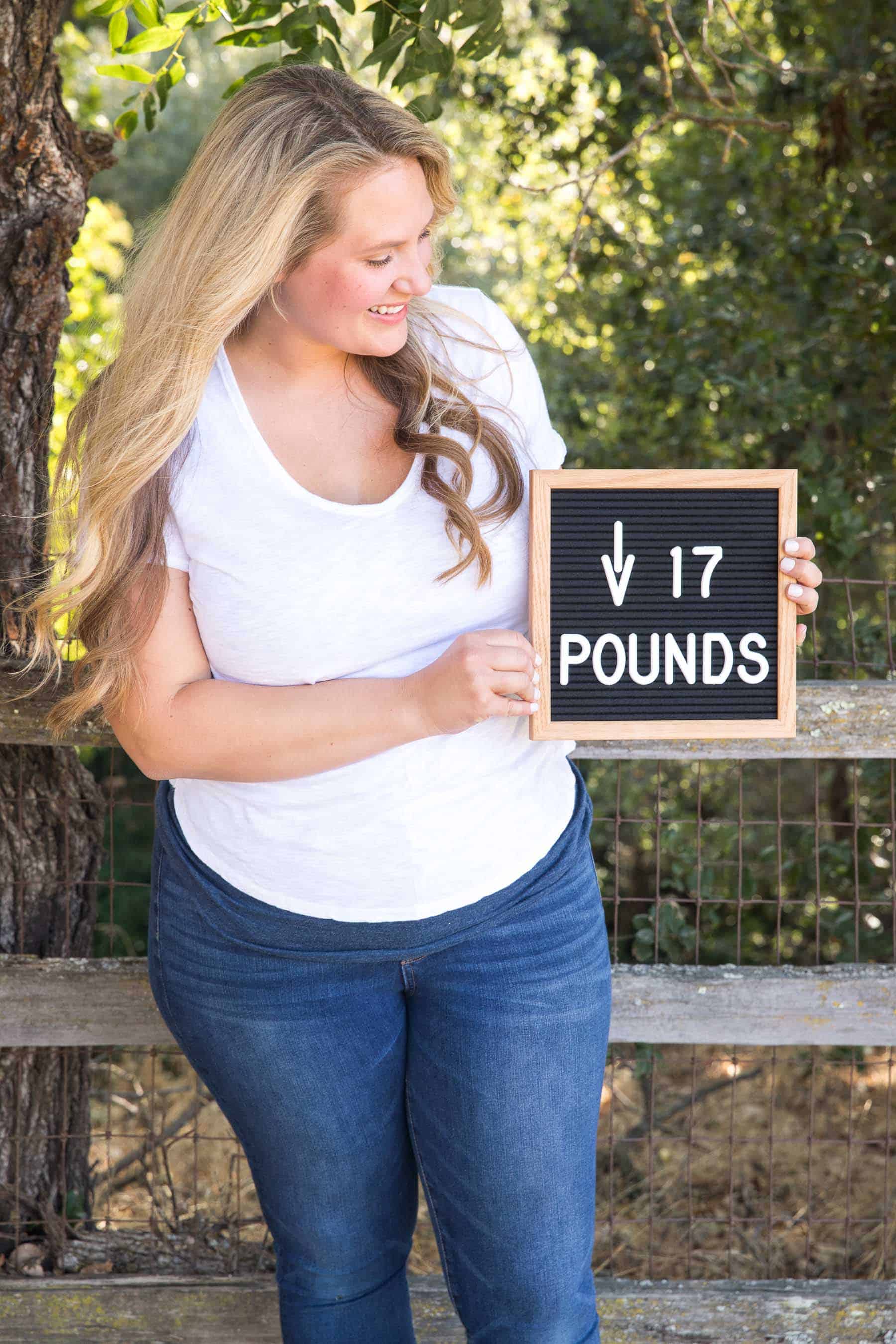 blond girl holding a sign that says "down 17 pounds"