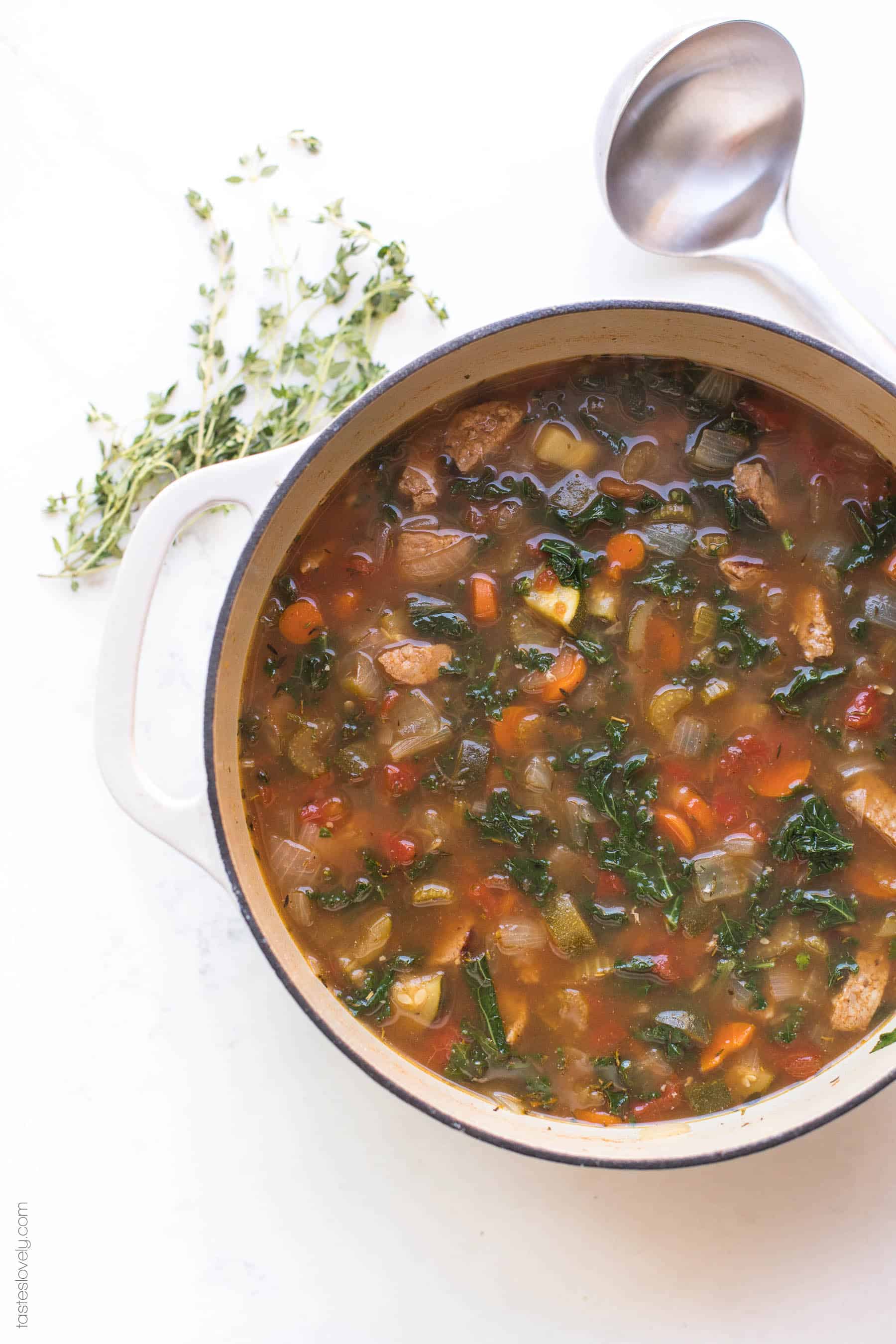 A dutch oven filled with sausage and kale vegetable soup