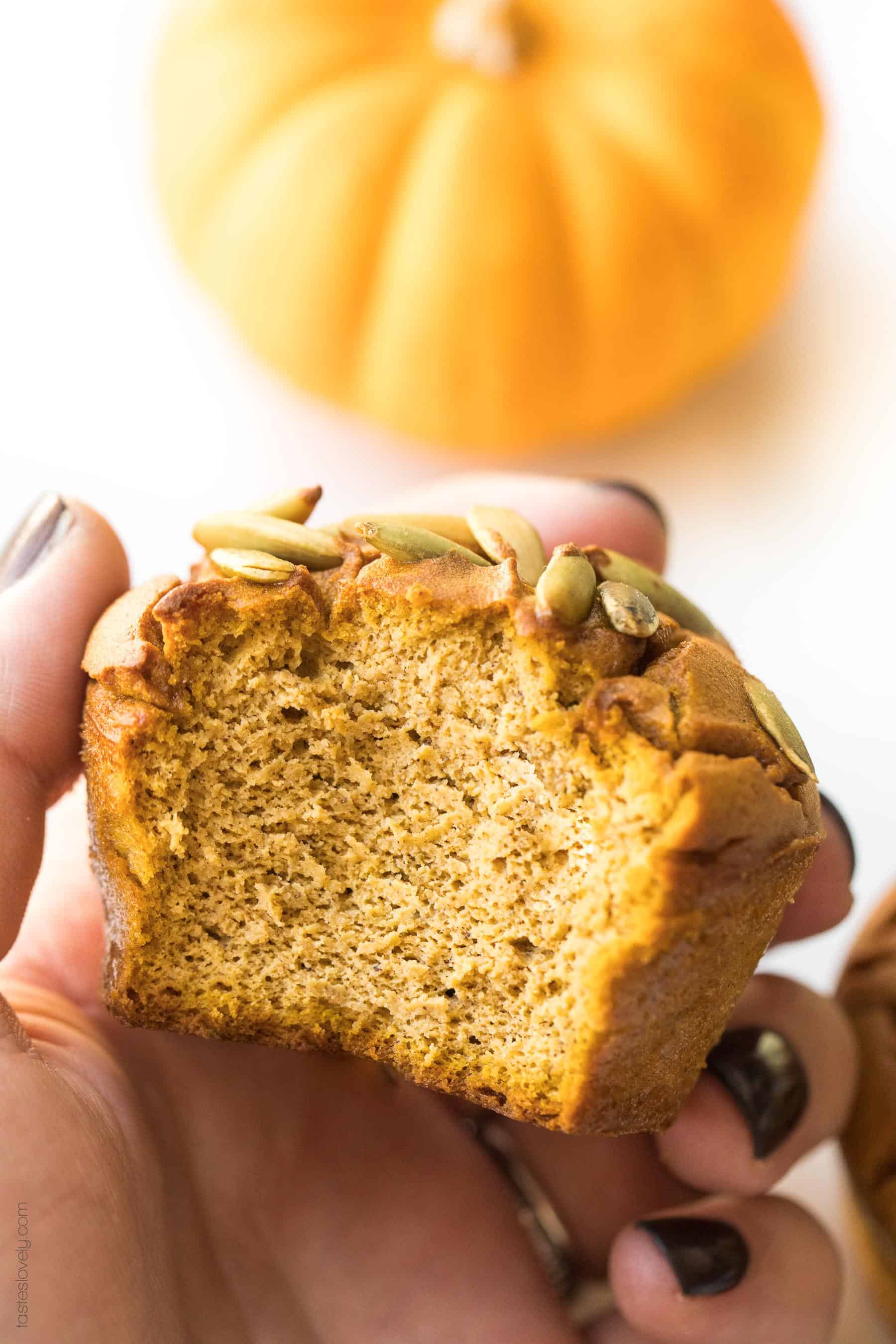 a hand holding a paleo pumpkin muffin that has a bite taken out of it