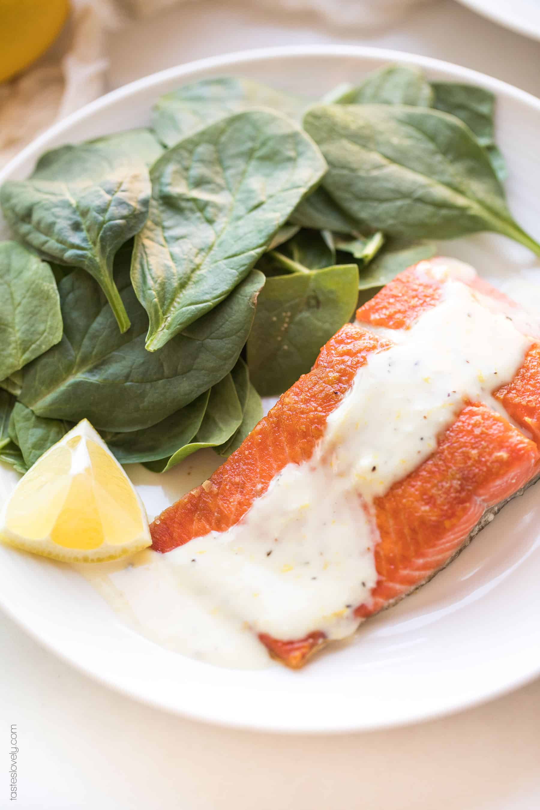 Salmon with a white sauce lemon garlic aioli on a plate with spinach