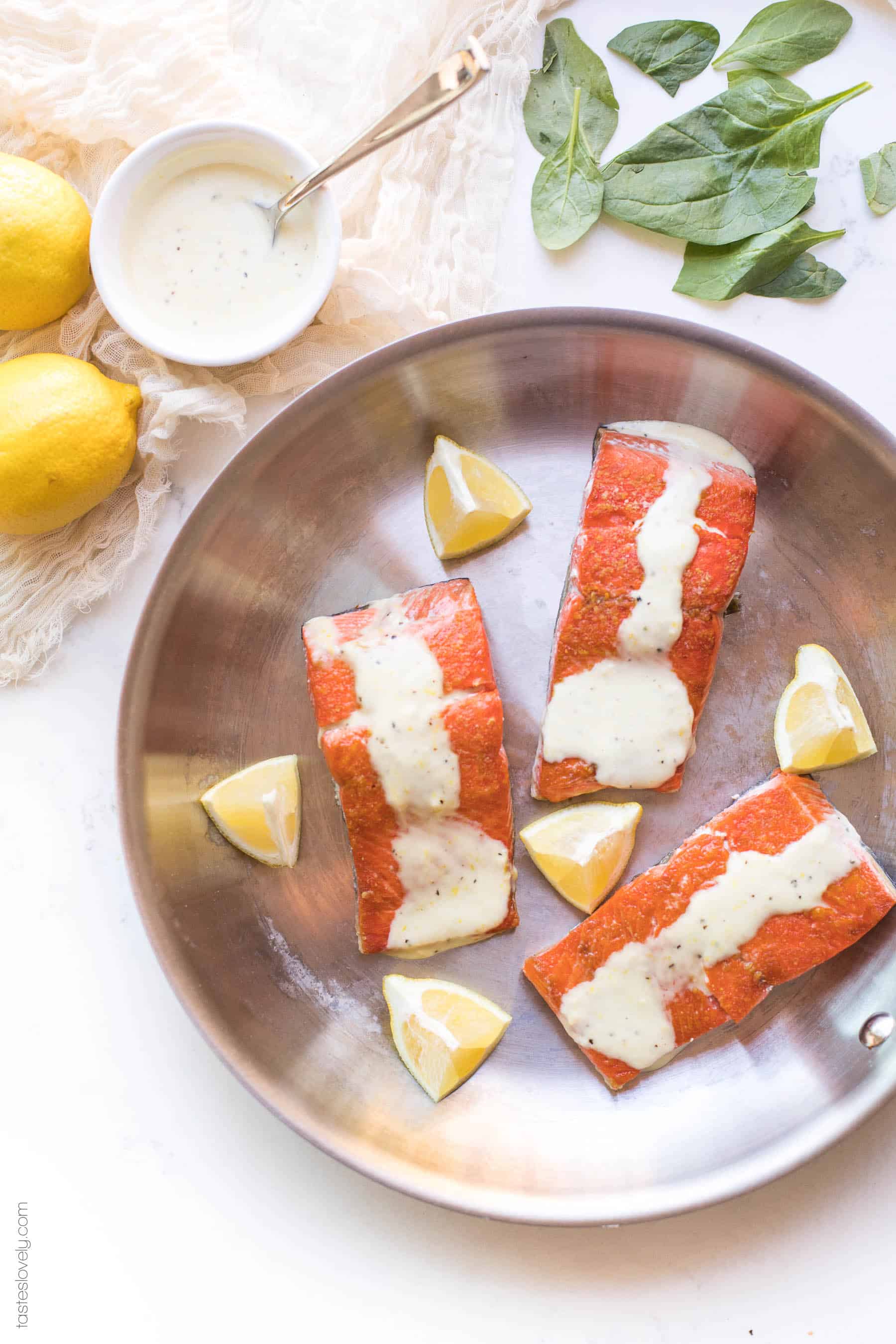 Salmon in a skillet topped with a white sauce lemon garlic aioli