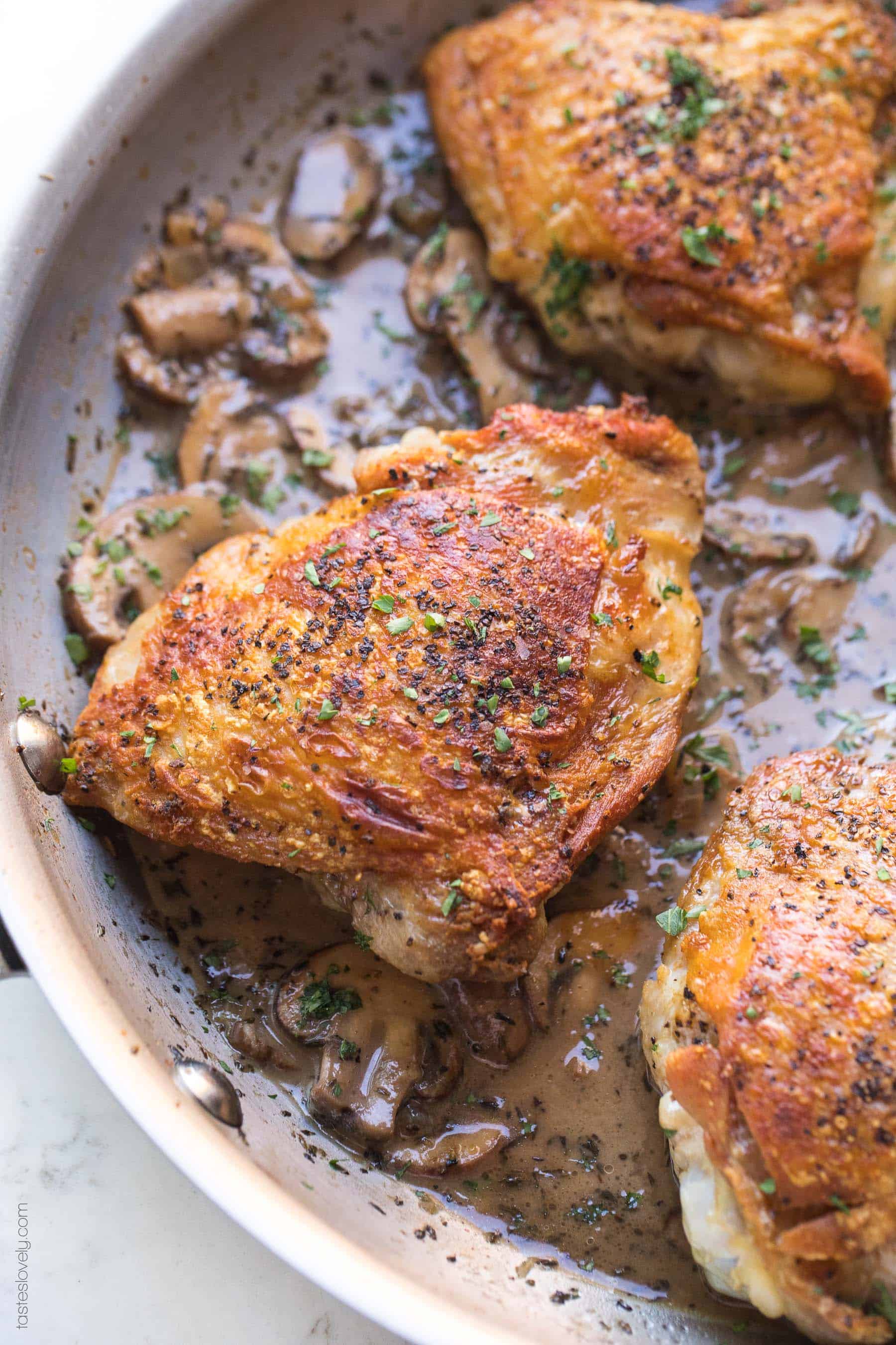 Crispy chicken thighs in a skillet with creamy mushroom sauce