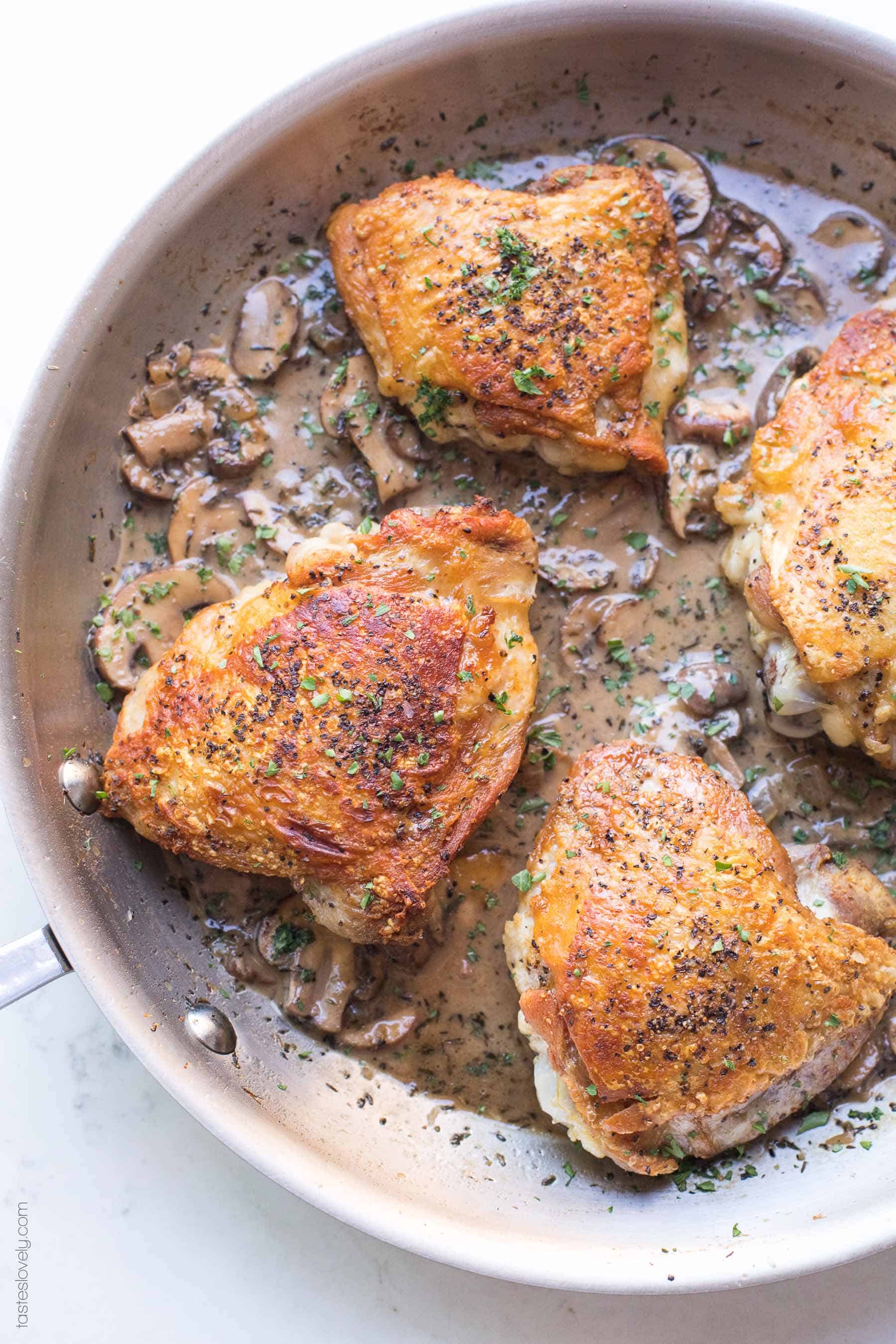 Crispy chicken thighs in a skillet with creamy mushroom sauce