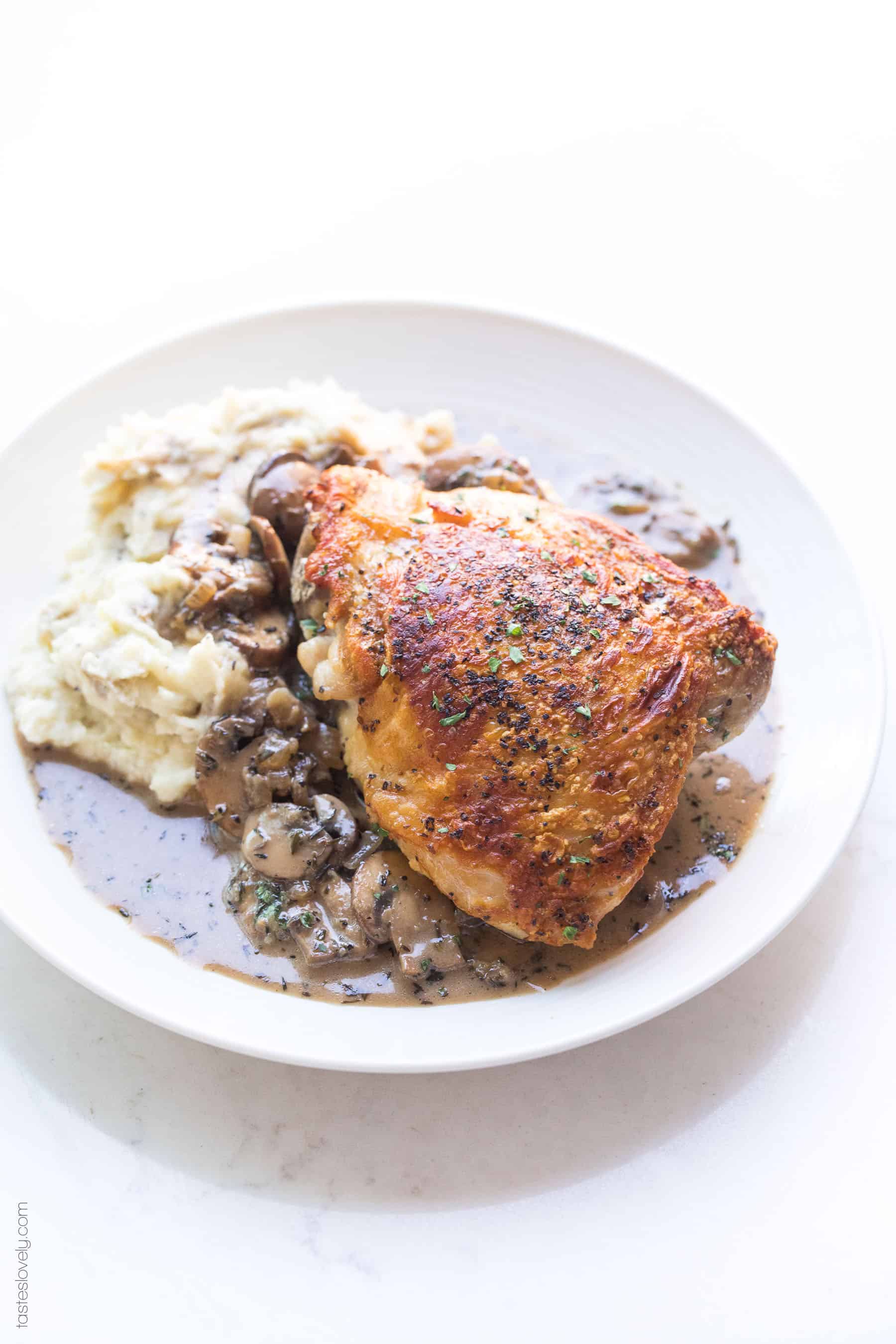 Crispy chicken thighs on a plate with mashed potatoes and creamy mushroom sauce