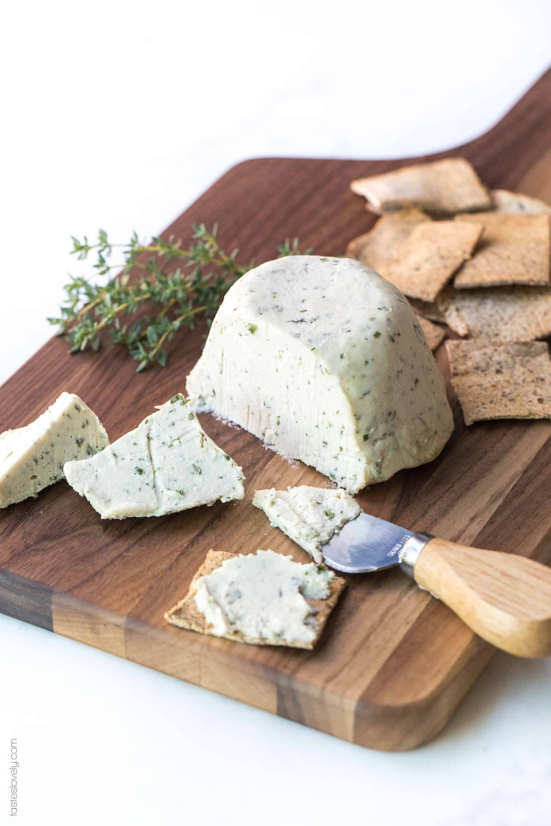 Cheese on a board sliced with crackers and herbs