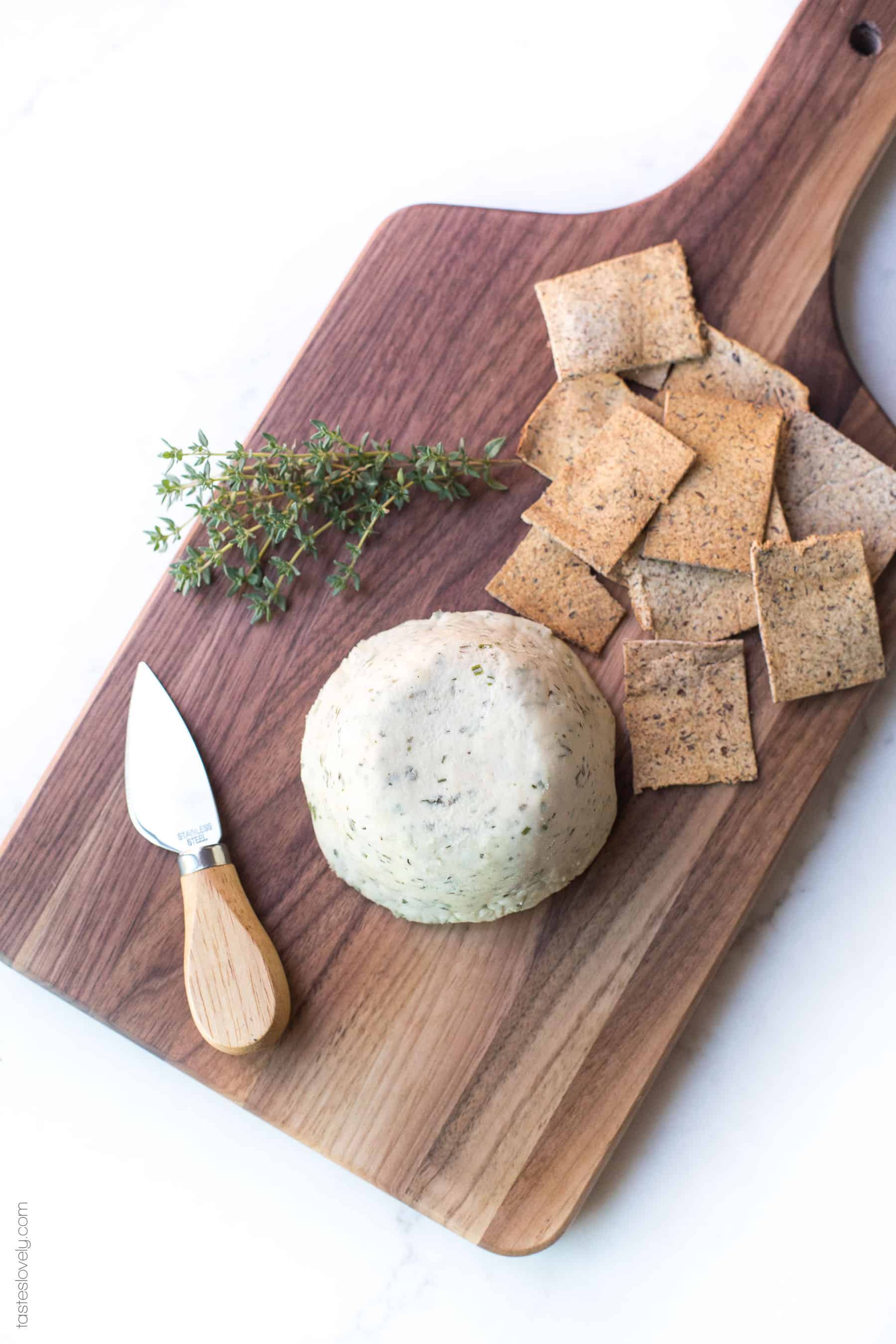 Cheese on a board sliced with crackers and herbs