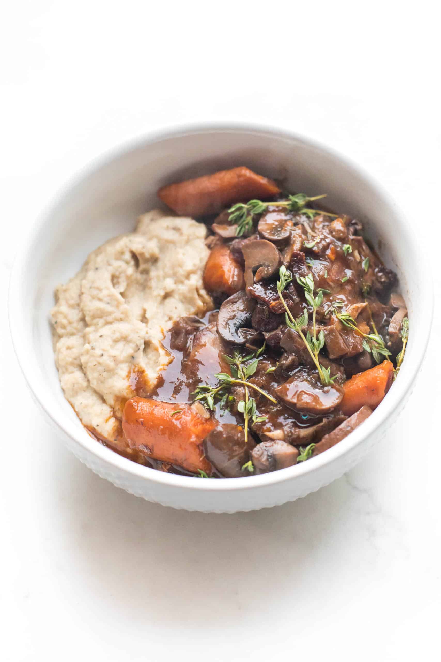 keto instant pot coq au vin with mashed cauliflower in a white bowl on a white background