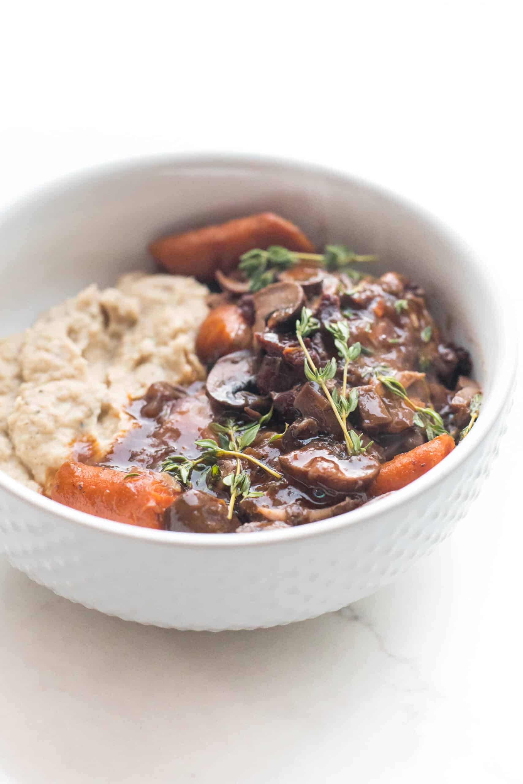 keto instant pot coq au vin with mashed cauliflower in a white bowl on a white background