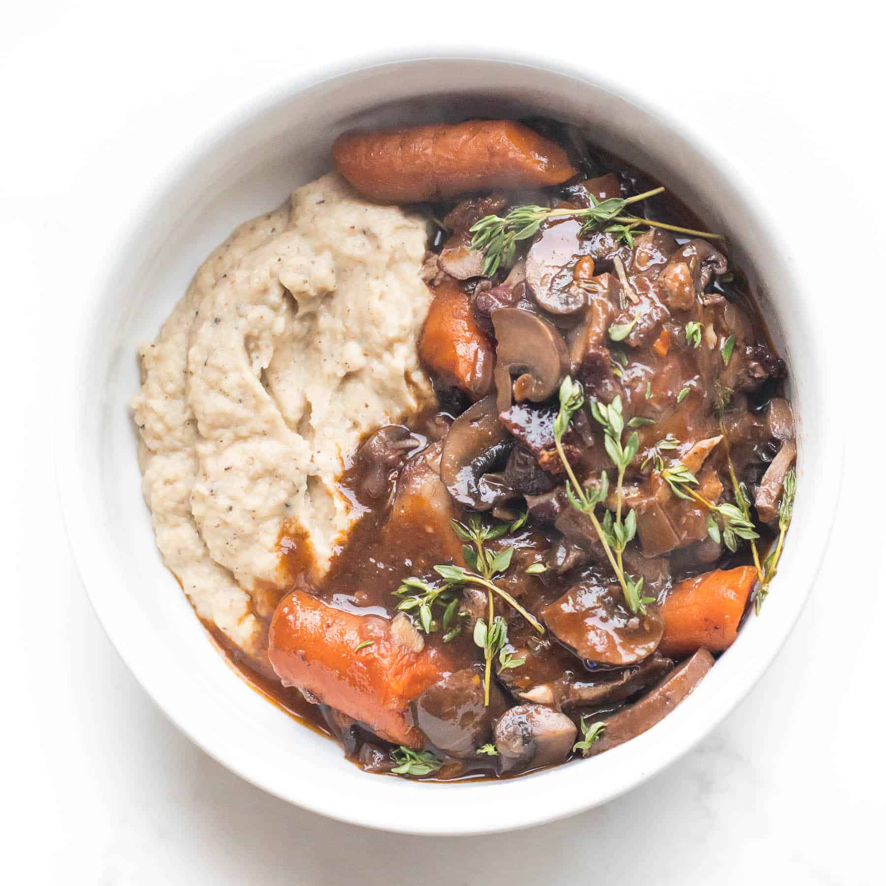 keto instant pot coq au vin with mashed cauliflower in a white bowl on a white background