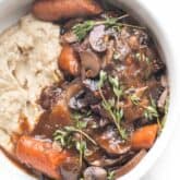 keto instant pot coq au vin with mashed cauliflower in a white bowl on a white background