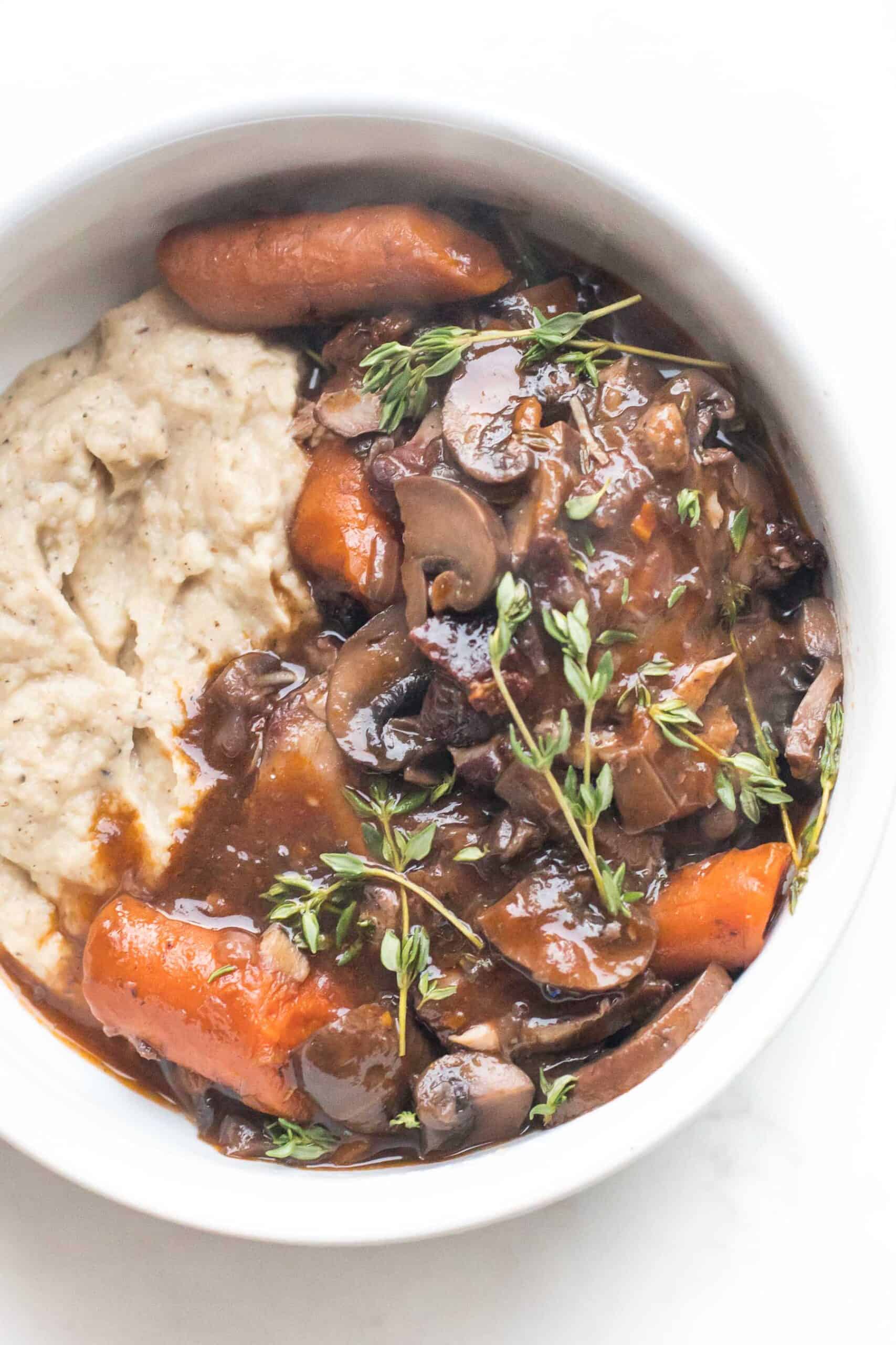 keto instant pot coq au vin with mashed cauliflower in a white bowl on a white background