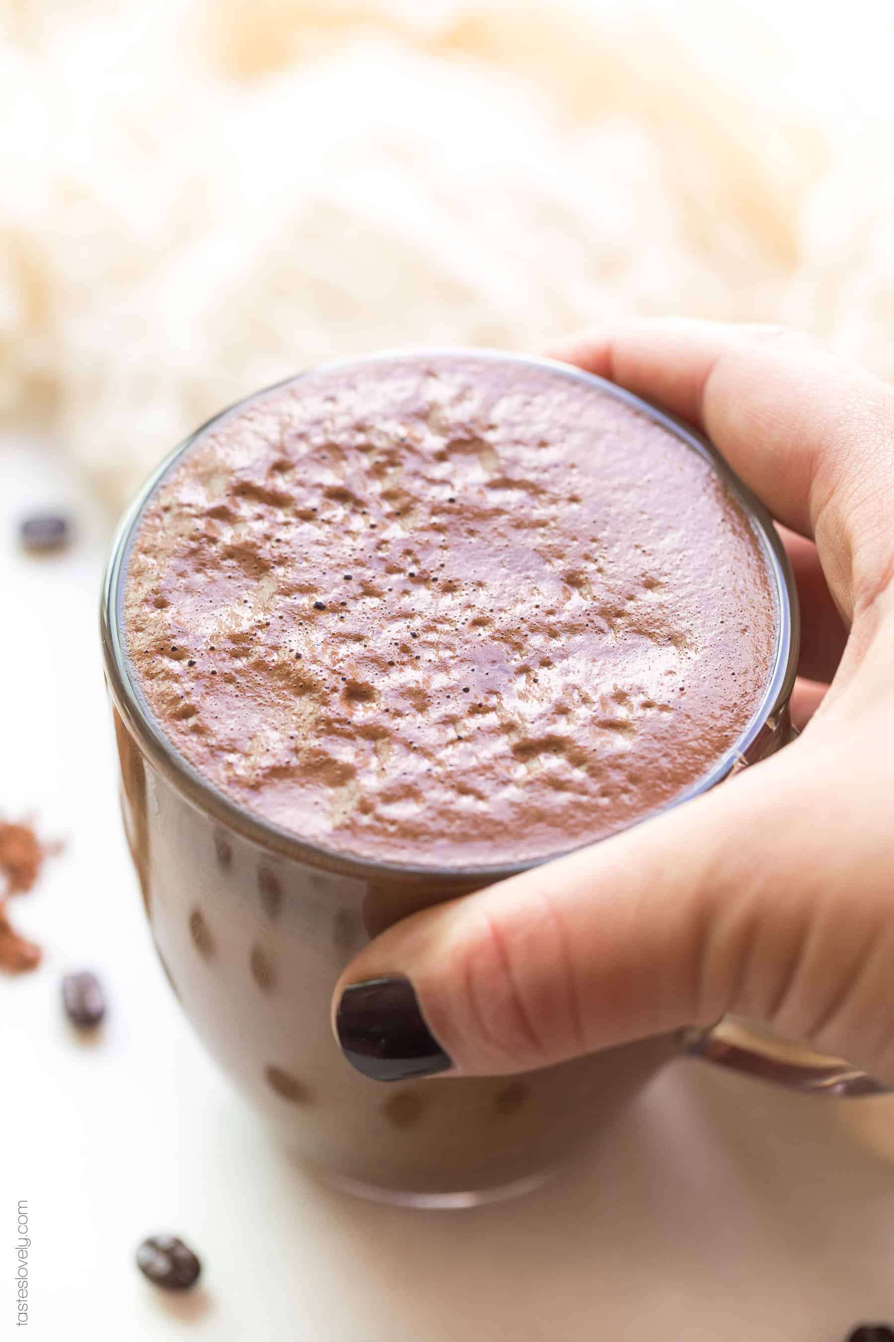 A hand holding a mocha in a clear glass