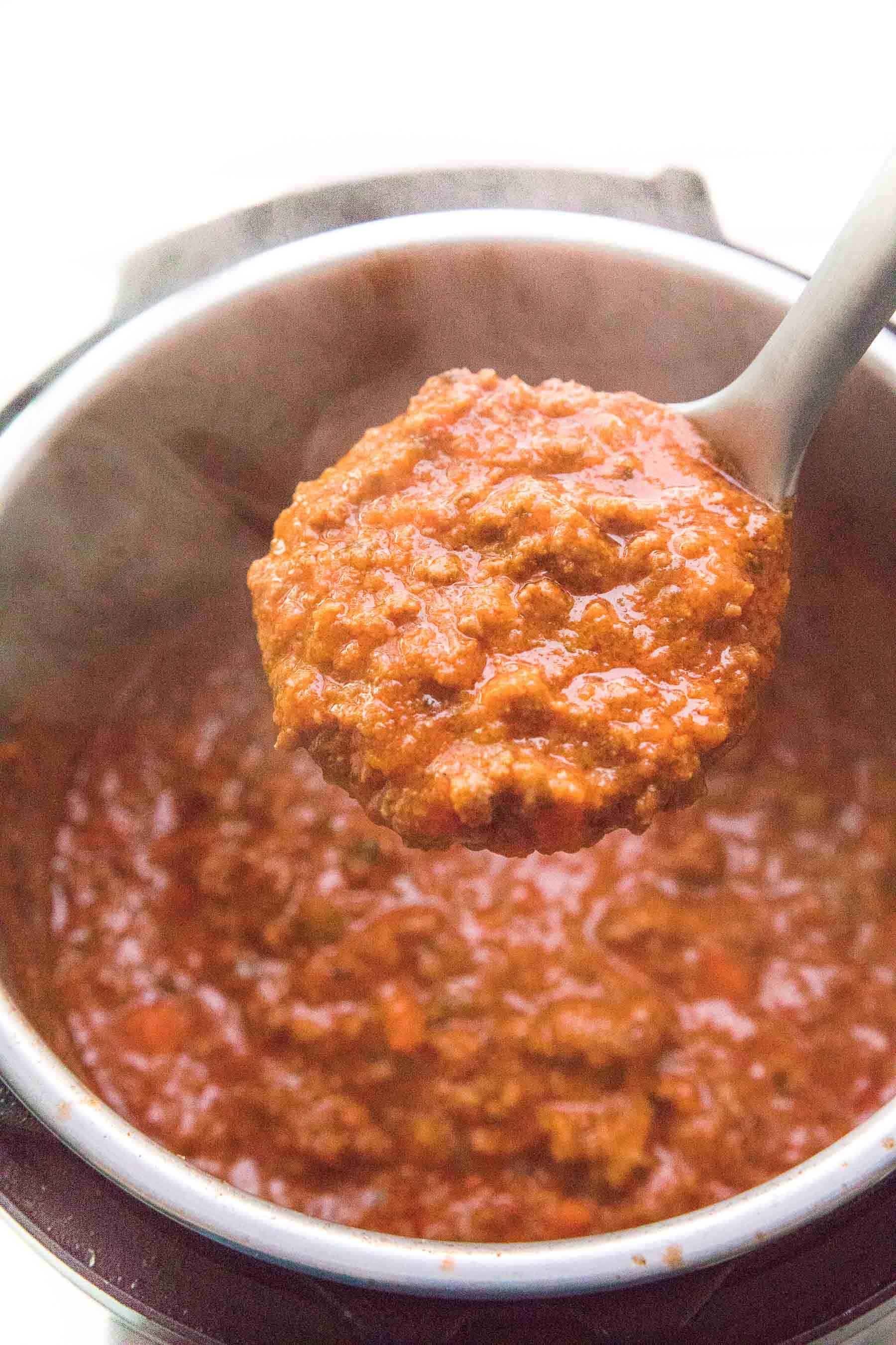 full ladle spooning out bolognese sauce from an instant pot