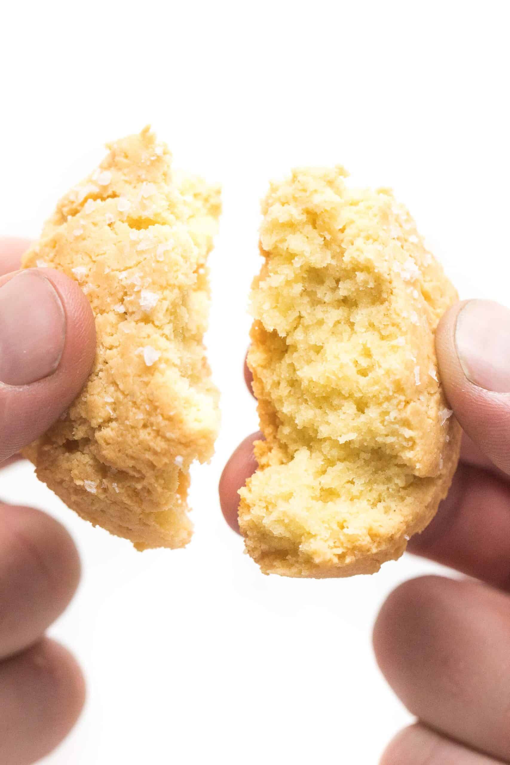 hand breaking apart a biscuit on a white background