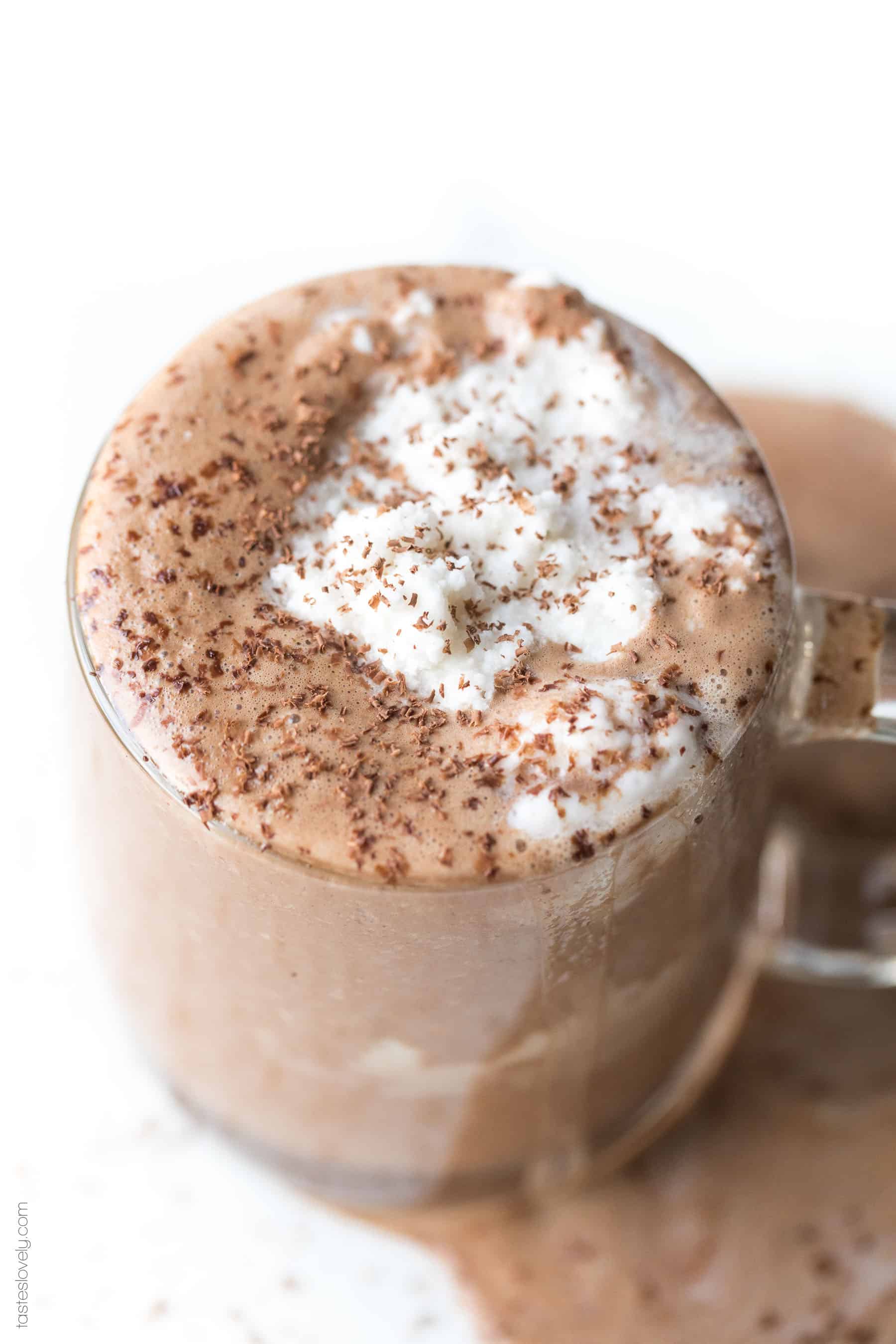 Hot chocolate in a clear mug topped with whipped cream and shaved chocolate