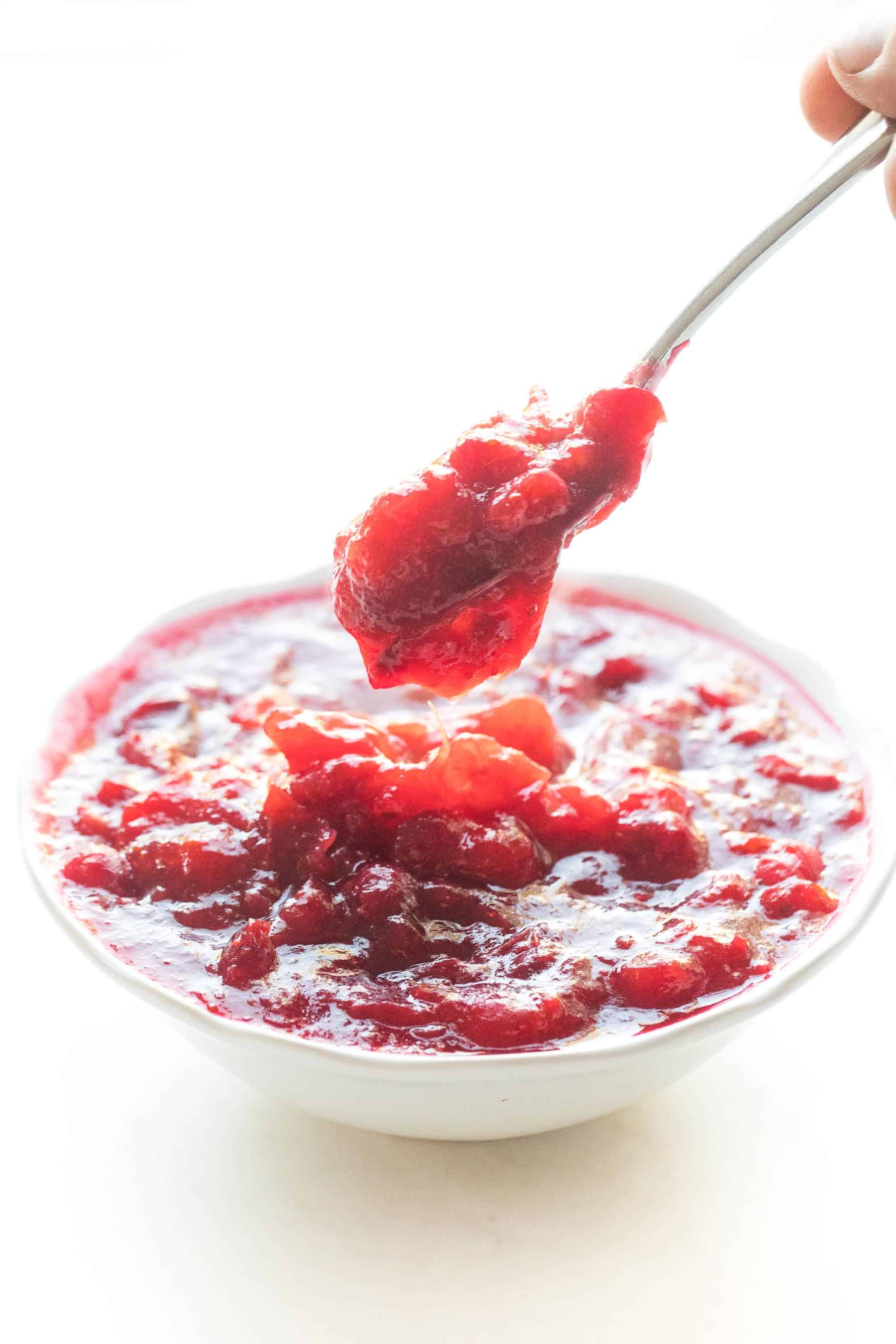 spoon dripping cranberry sauce in a white bowl