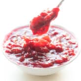 spoon dripping cranberry sauce in a white bowl