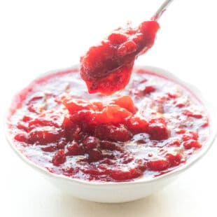 spoon dripping cranberry sauce in a white bowl