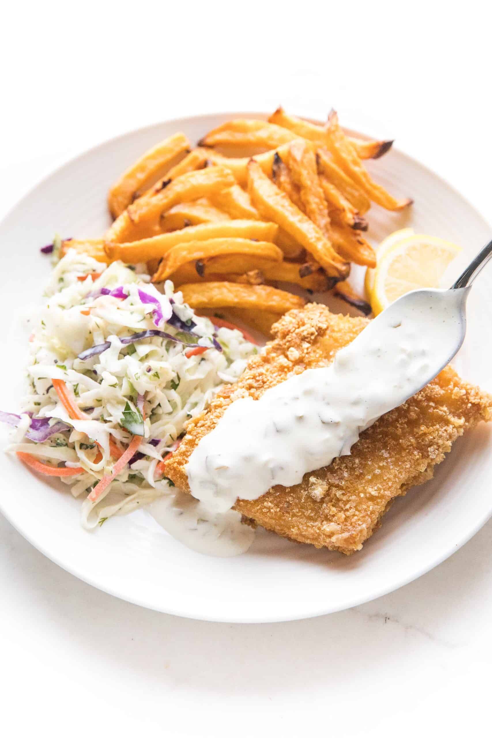 fish + chips with coleslaw + tartar sauce on a white plate